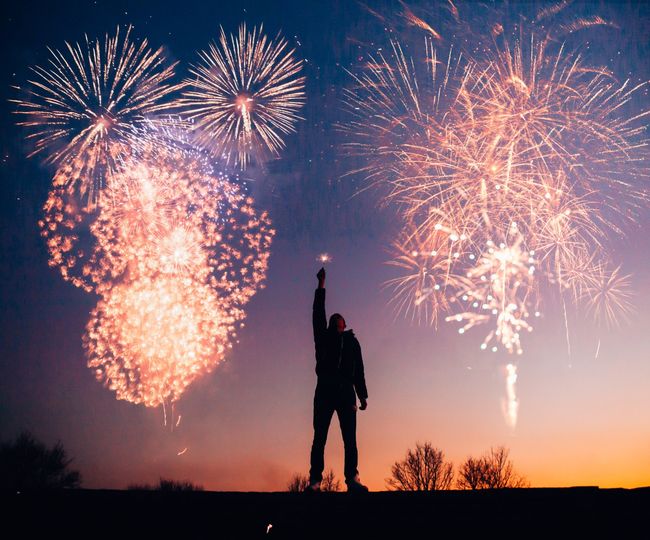 A man is standing in front of a fireworks display