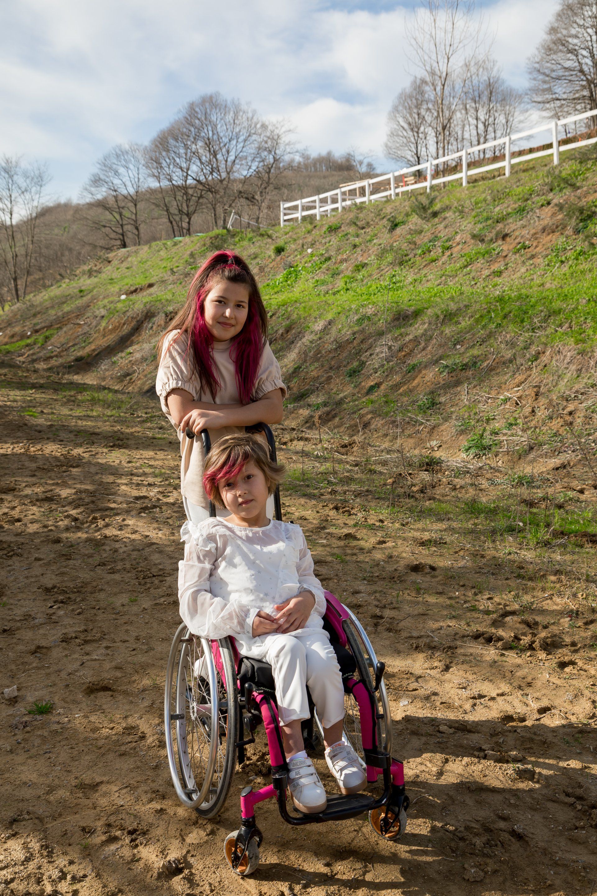 a woman standing behind a child in a wheelchair