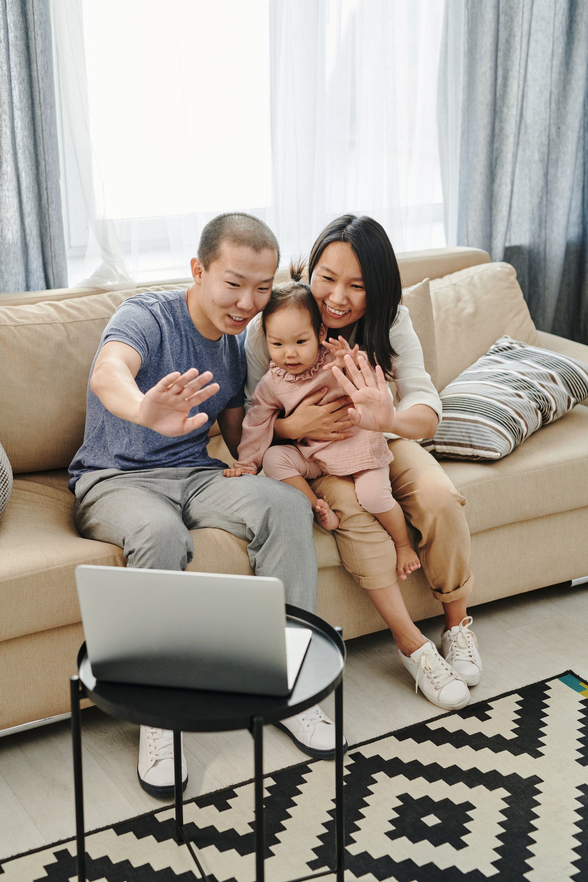 A family is sitting on a couch in front of a laptop computer.