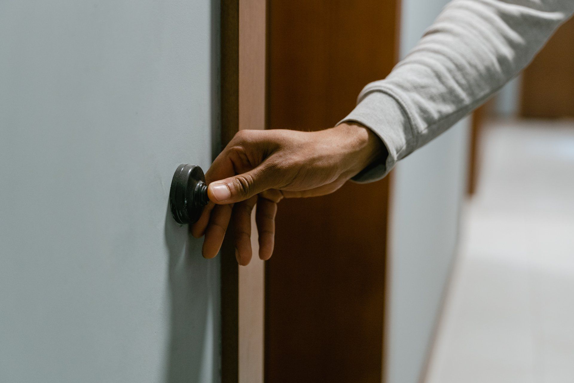 A person is pressing a doorbell in a hallway.