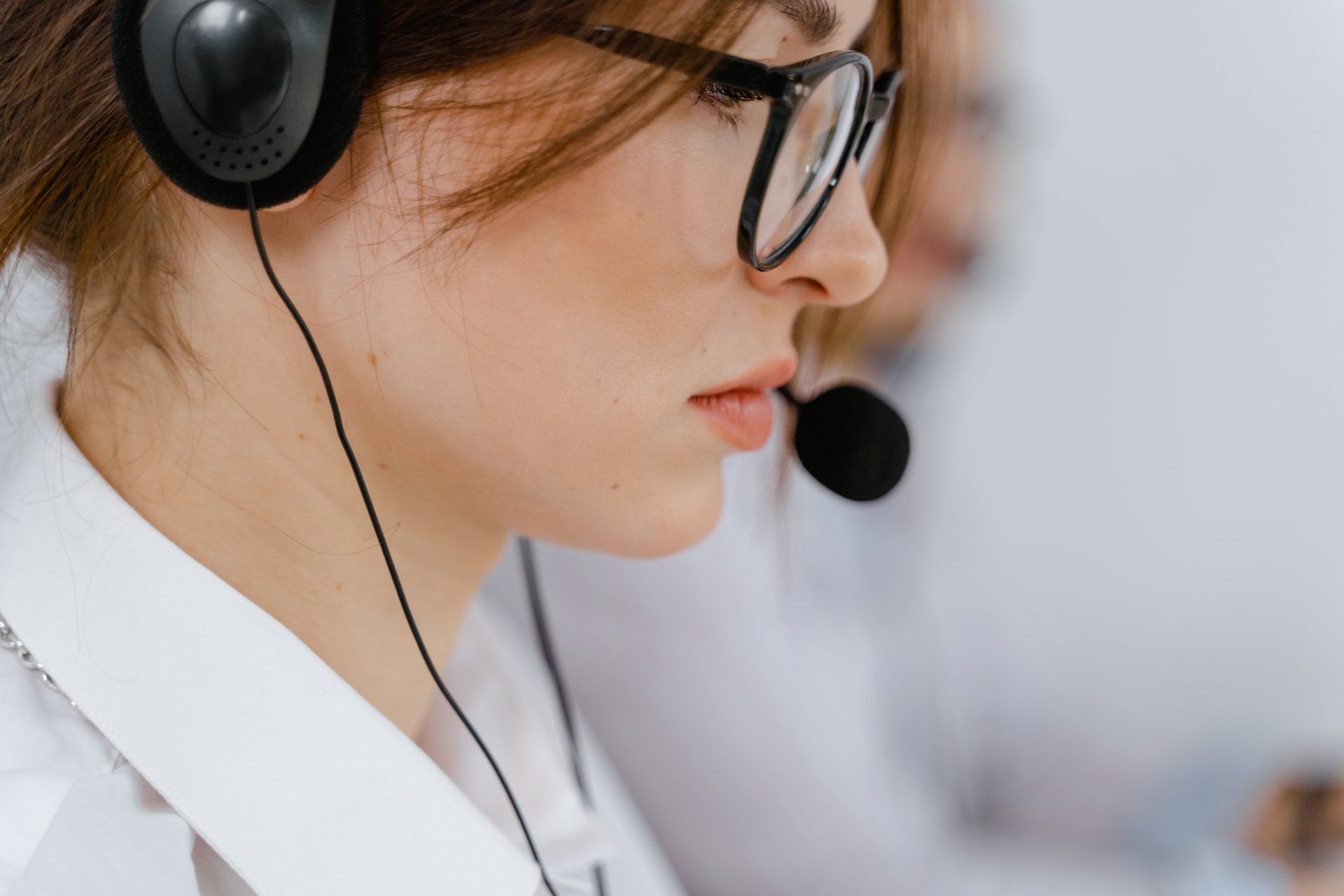 a woman wearing glasses and headphones is talking on a phone .