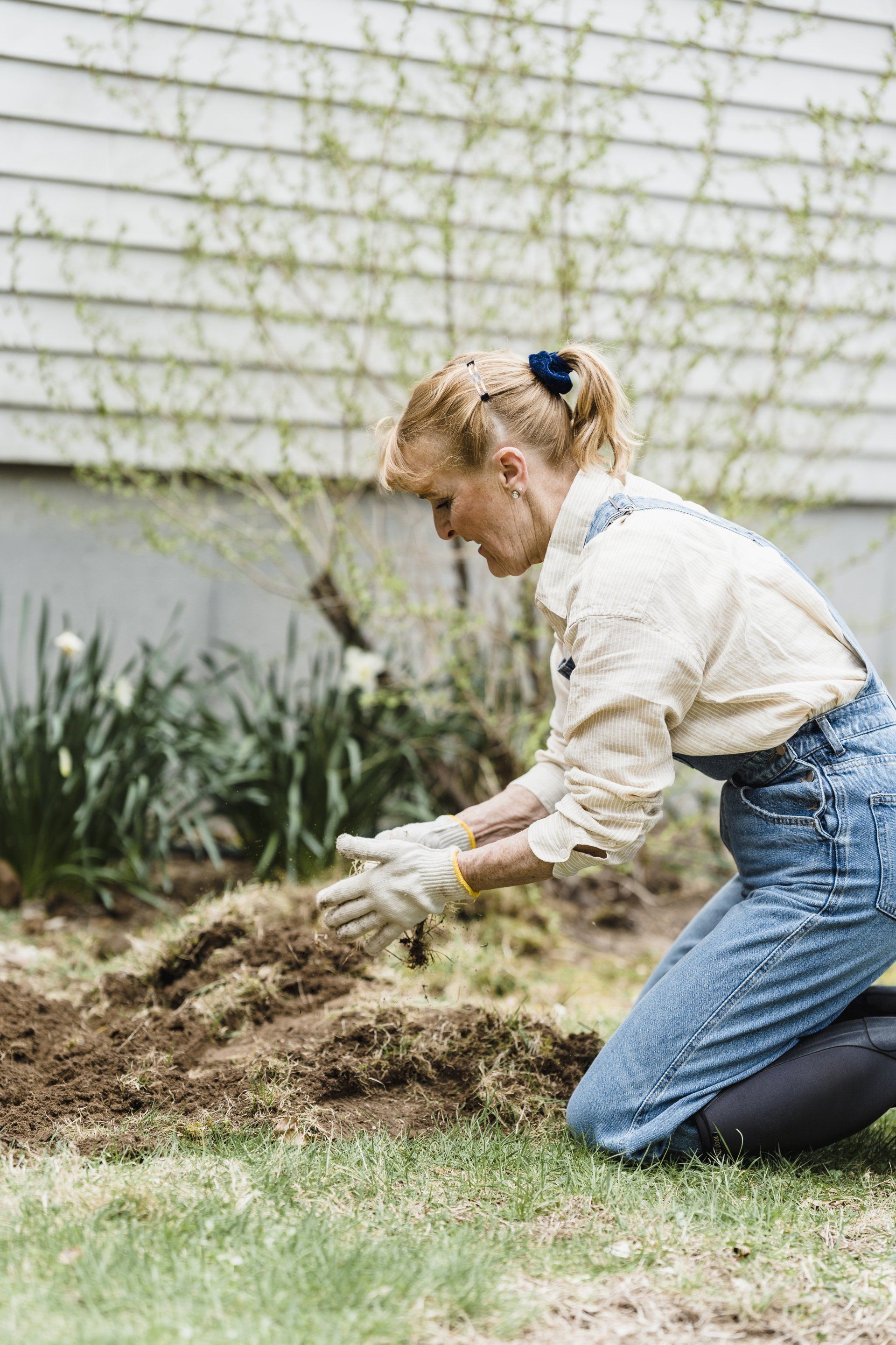 a woman putting a layer of grass on the soil