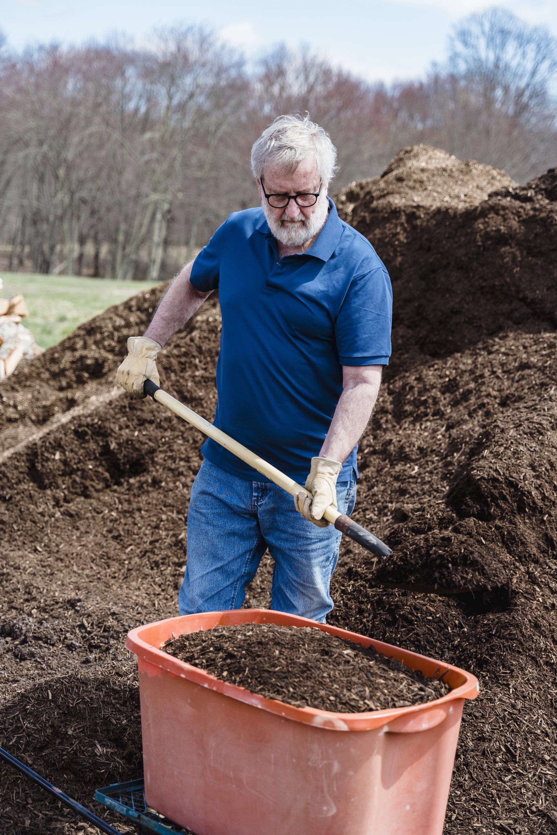 A man is shoveling dirt into a wheelbarrow.