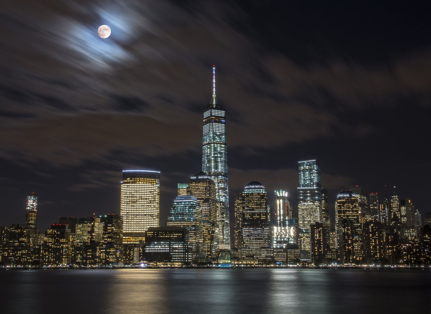 A city skyline at night with a full moon in the sky