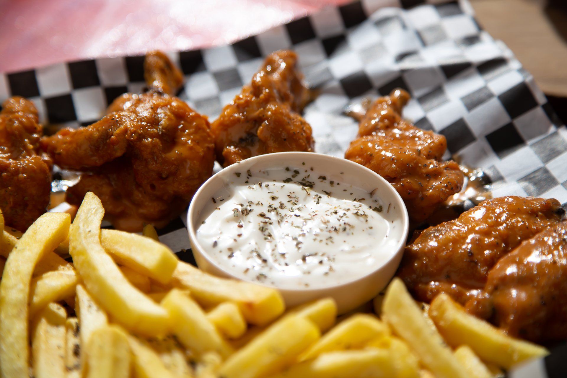 A plate of chicken wings and french fries with a bowl of dipping sauce