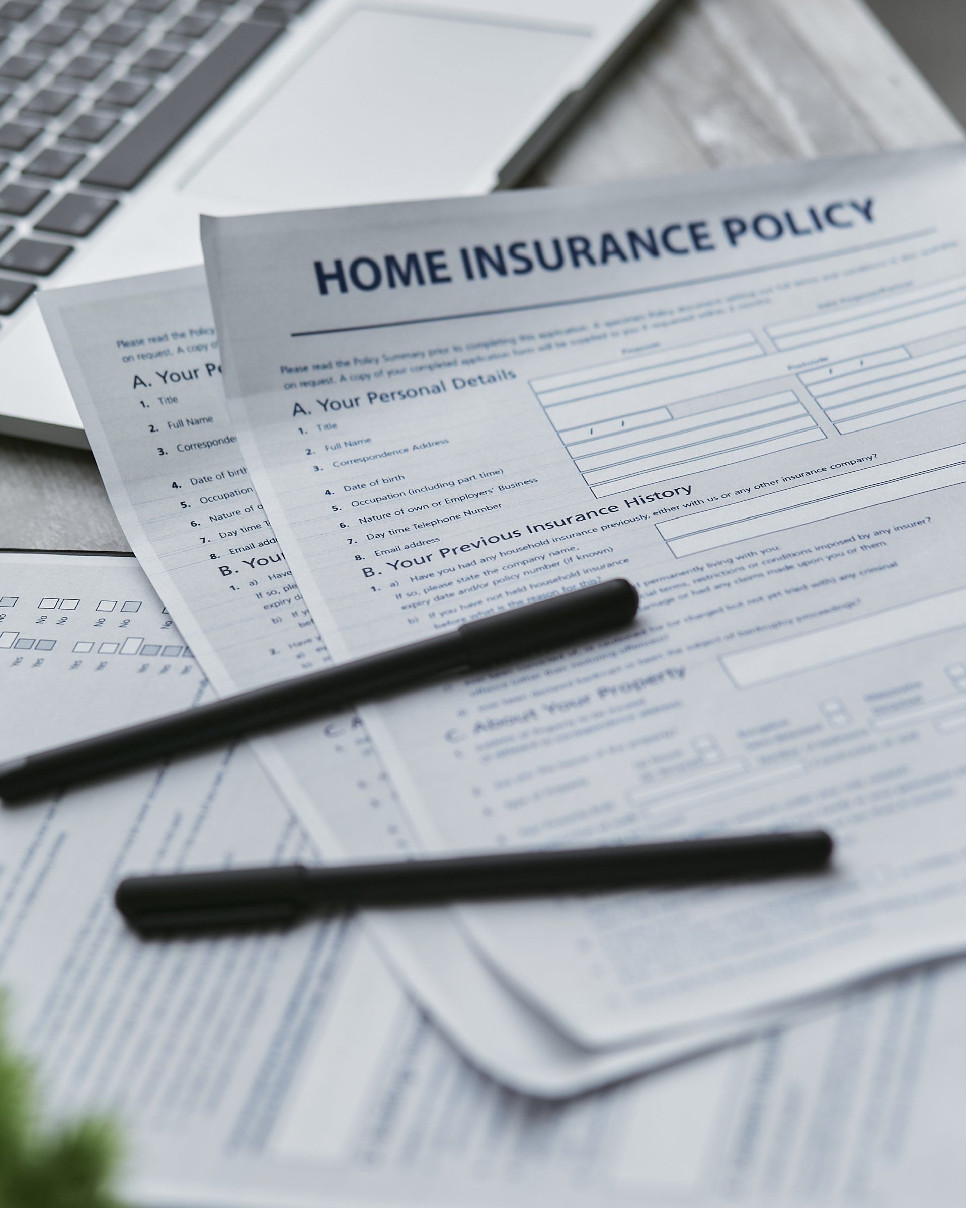 An insurance policy is sitting on a table next to a laptop.