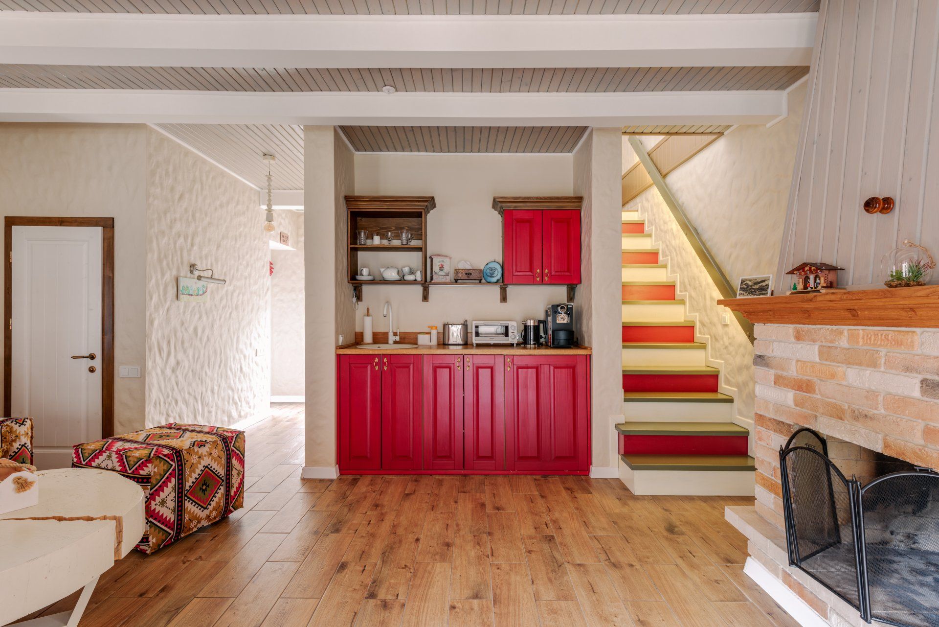 A living room with red cabinets , a fireplace and stairs leading up to the second floor.