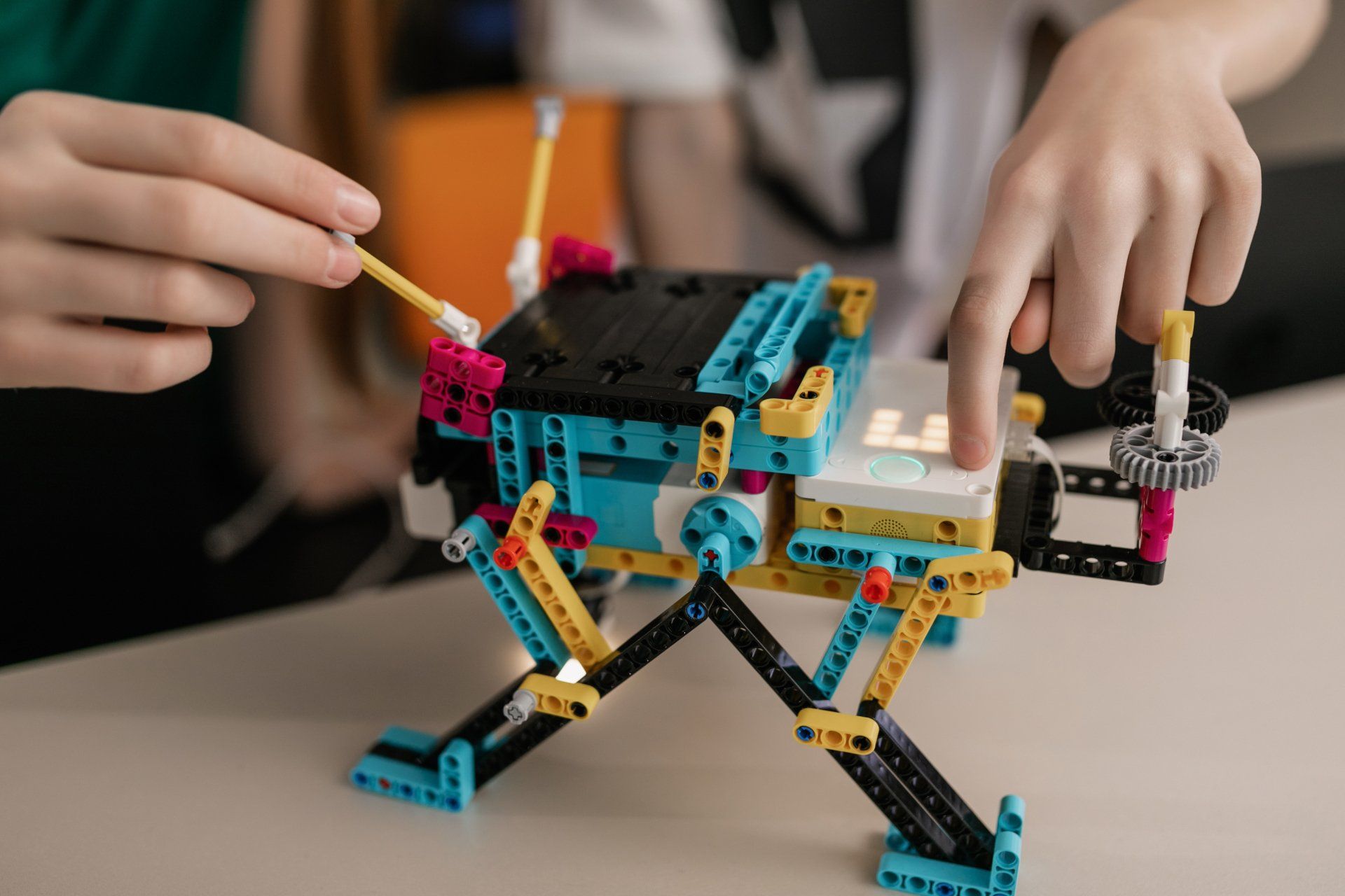 A person is playing with a lego robot on a table.