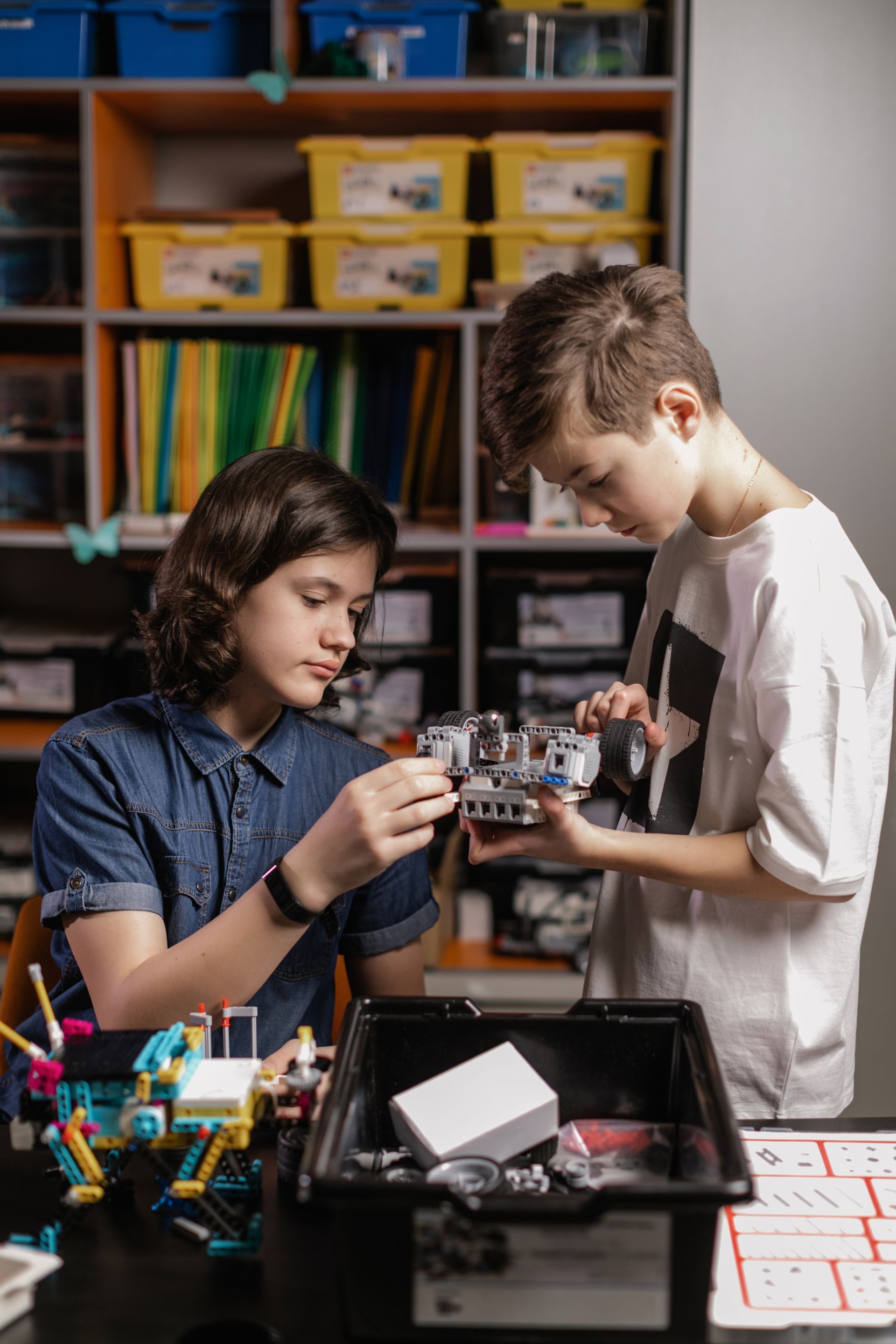 Two young boys are working on a robot in a lab.