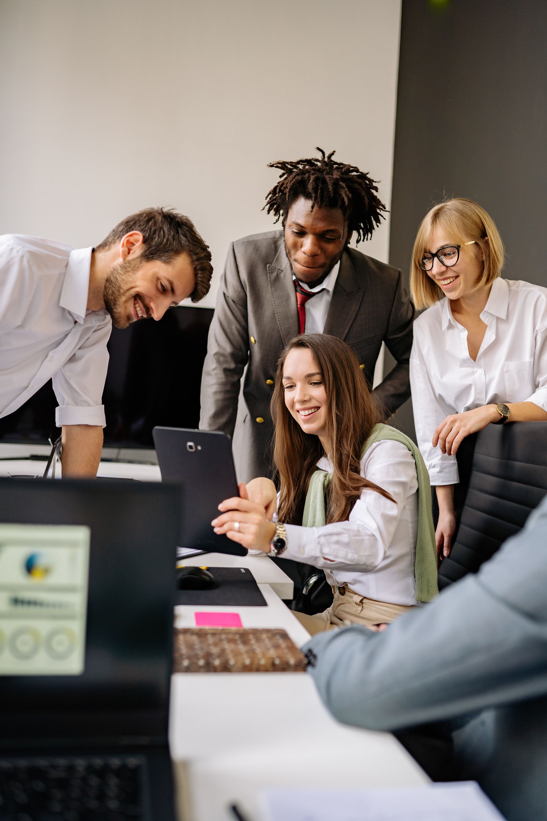 A group of people are looking at a laptop computer in an office.