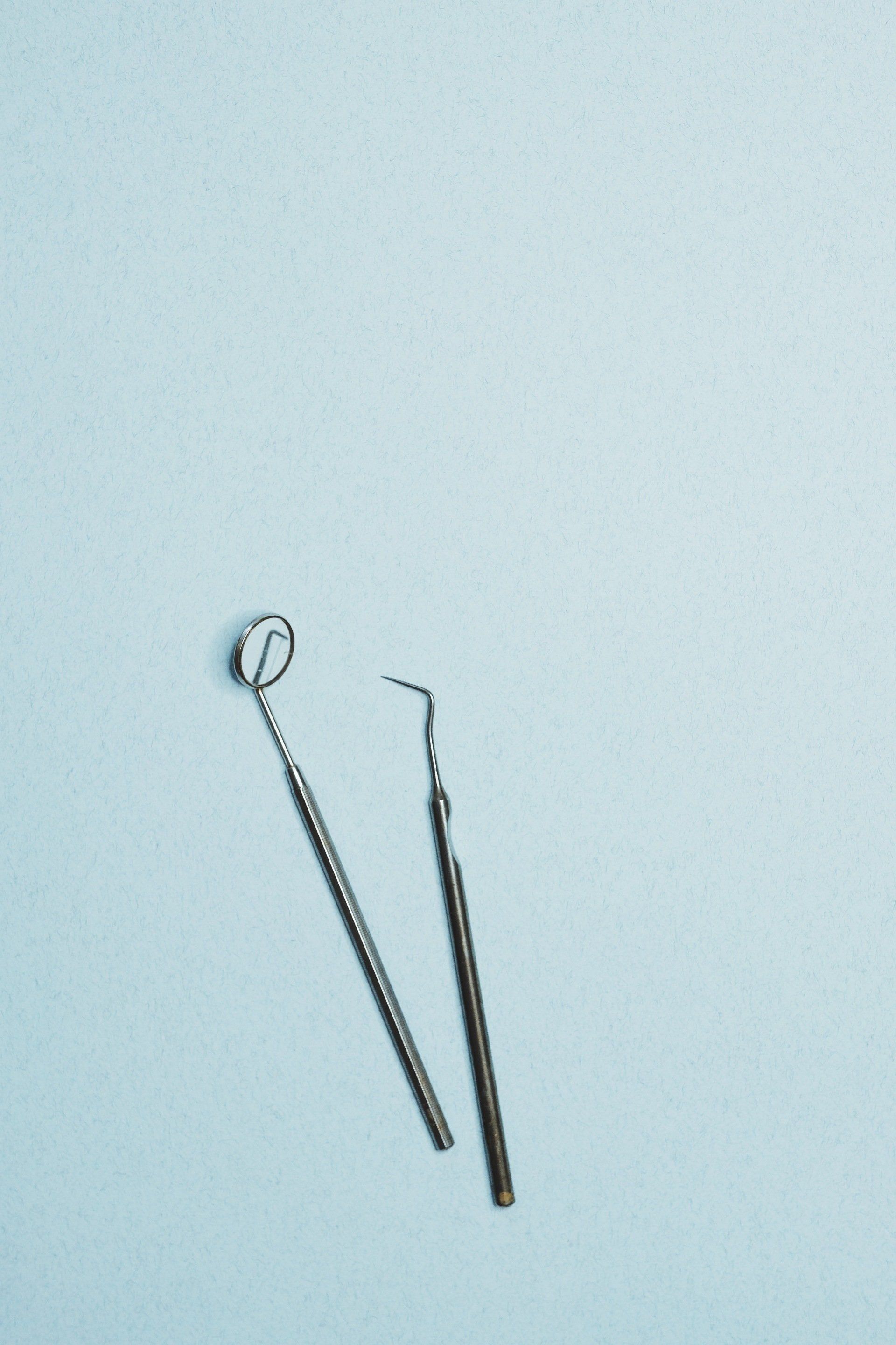 two dental instruments are sitting on a blue surface .