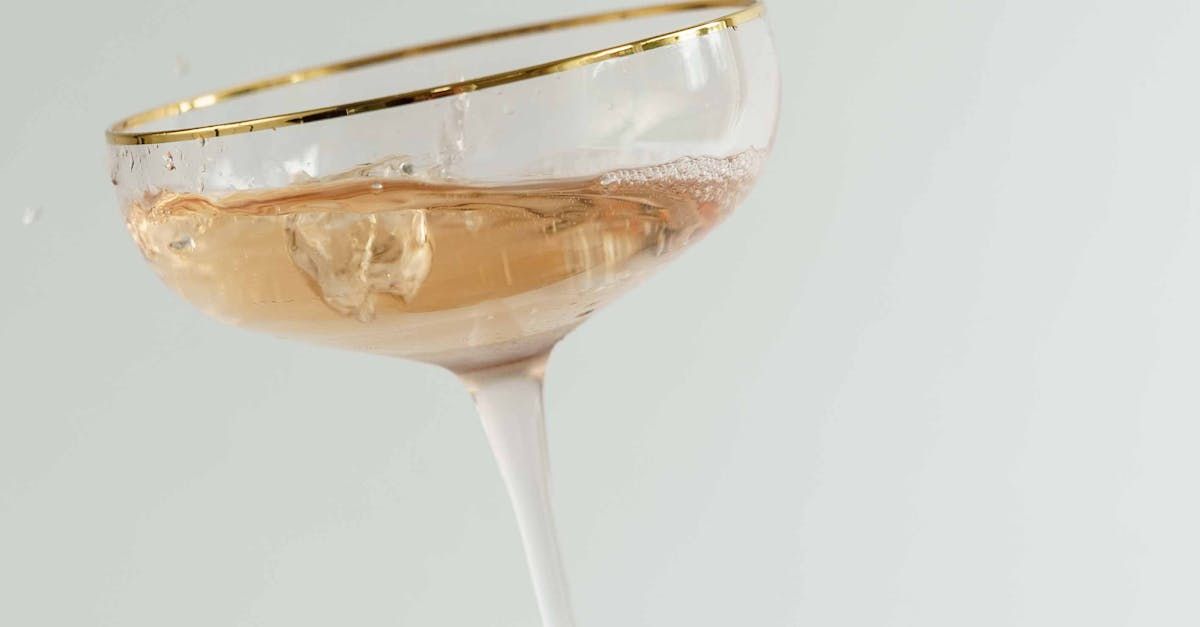 A close up of a champagne glass with a gold rim on a table.