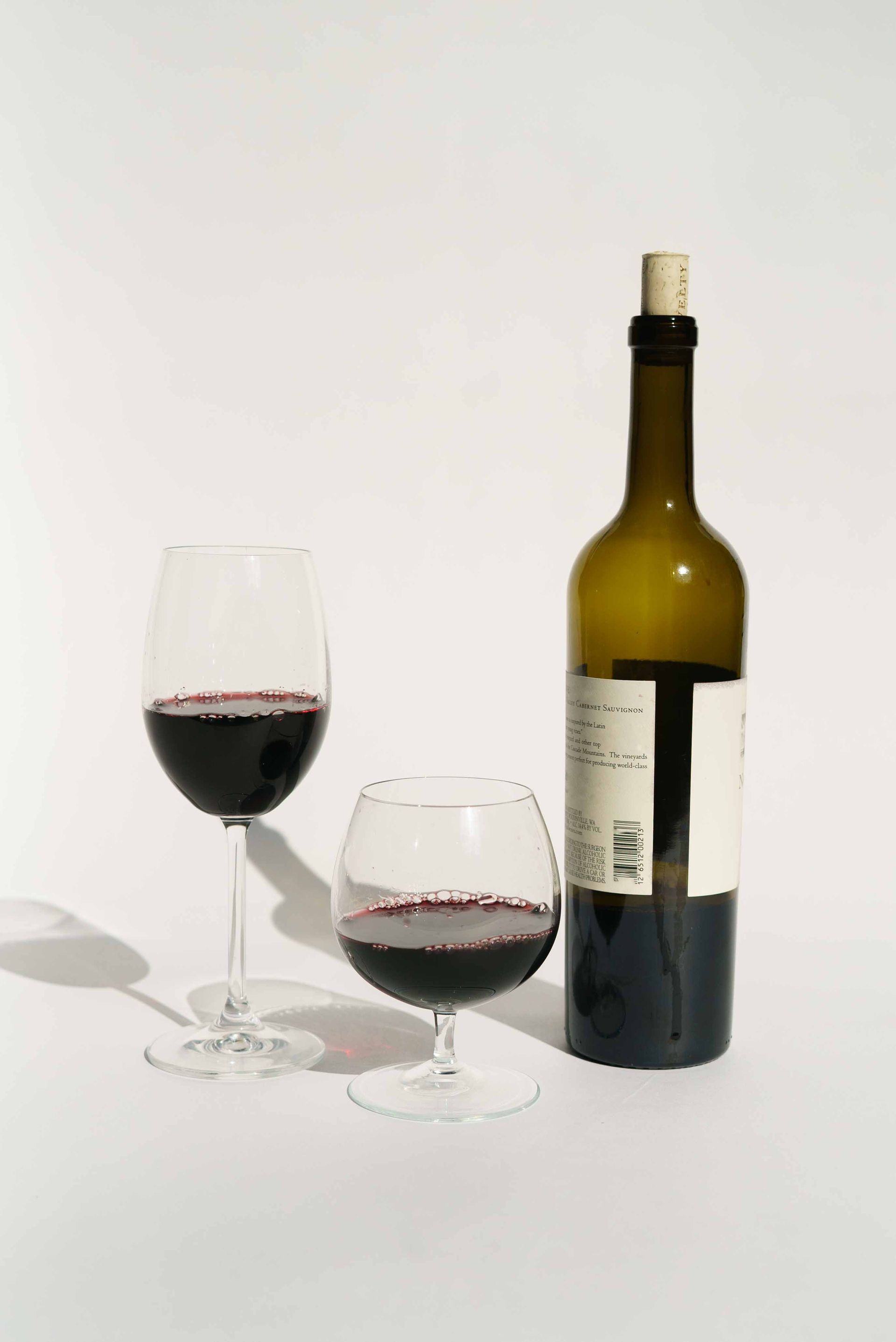 A bottle of wine and two glasses of wine are on a table.