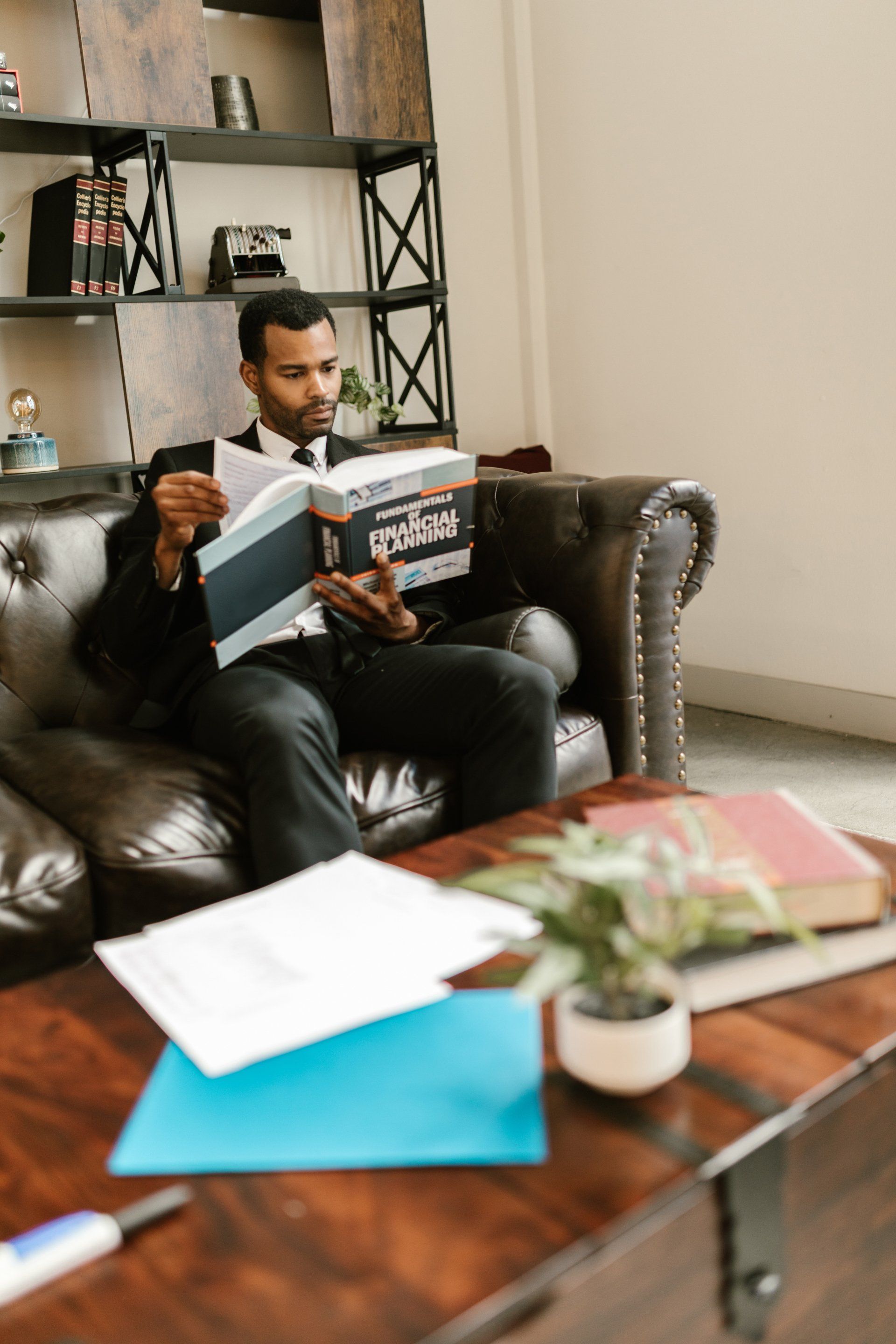 Man sat on sofa reading a book - Employee Wellbeing & Benefits