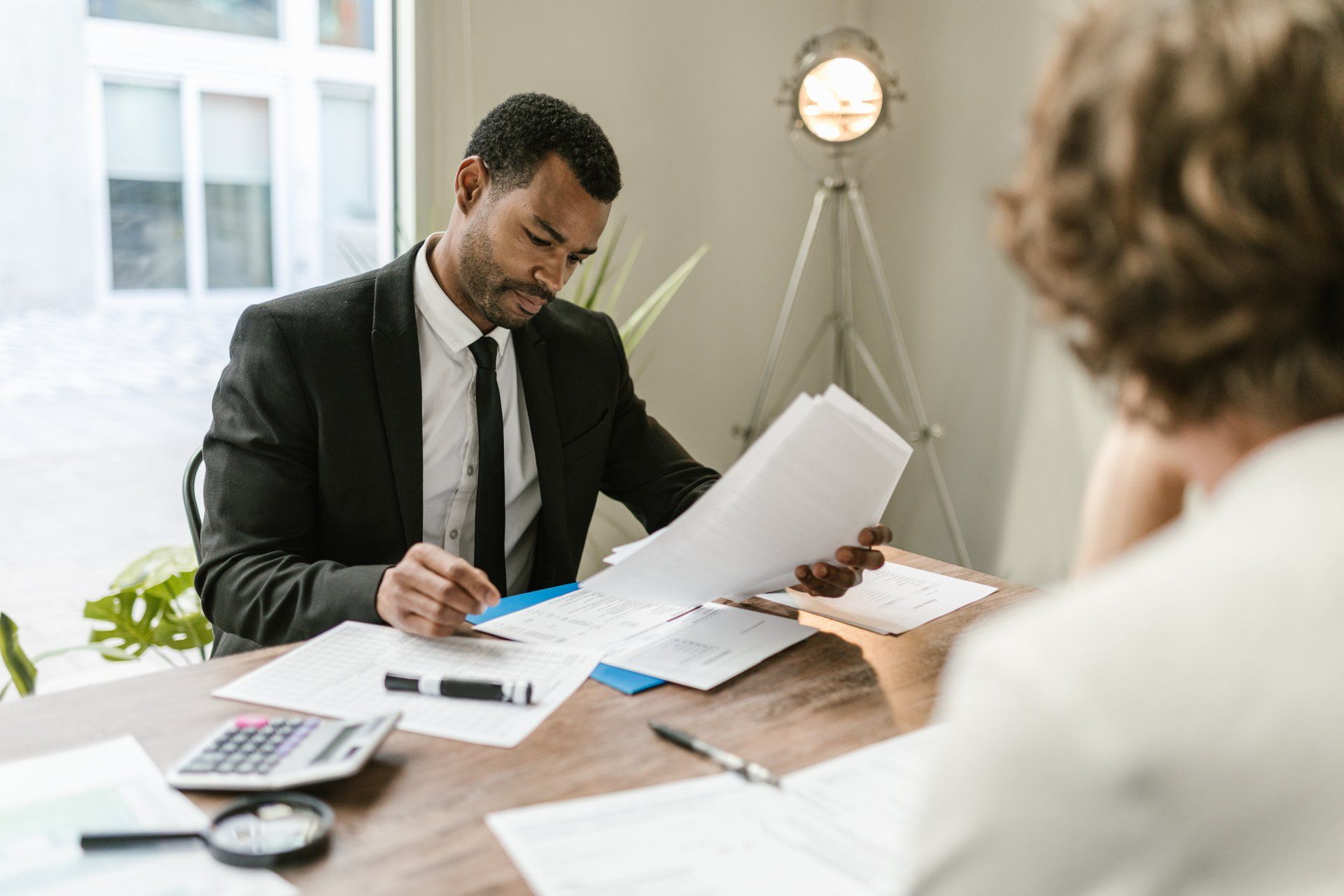 A man in a suit and tie is sitting at a table looking at papers.