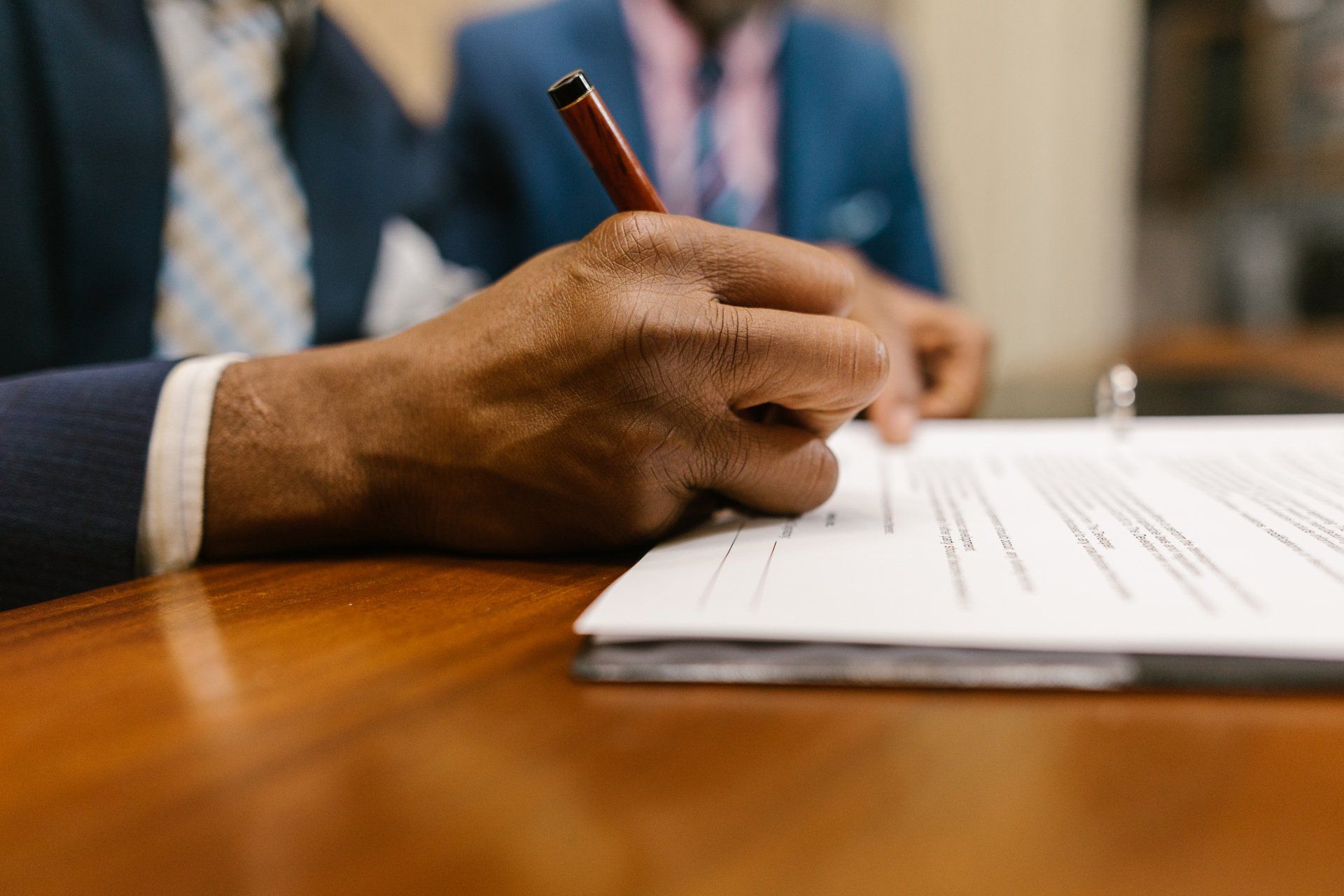 A man is writing on a piece of paper with a pen.