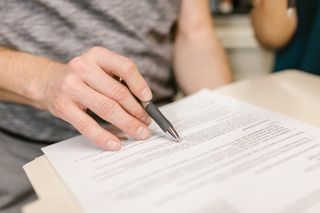 A person is writing on a piece of paper with a pen.