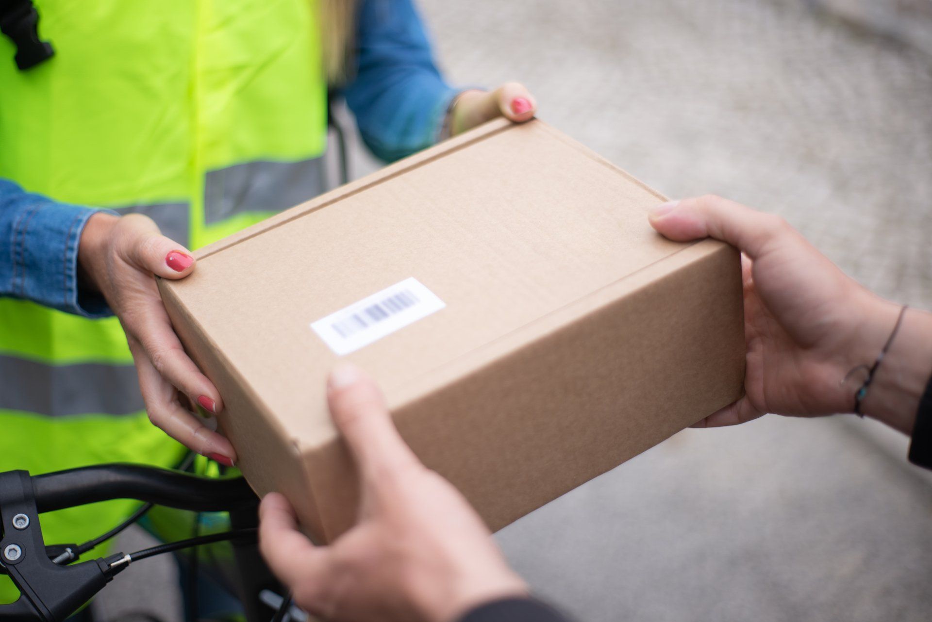A courier hands a same day rush delivered package to a customer