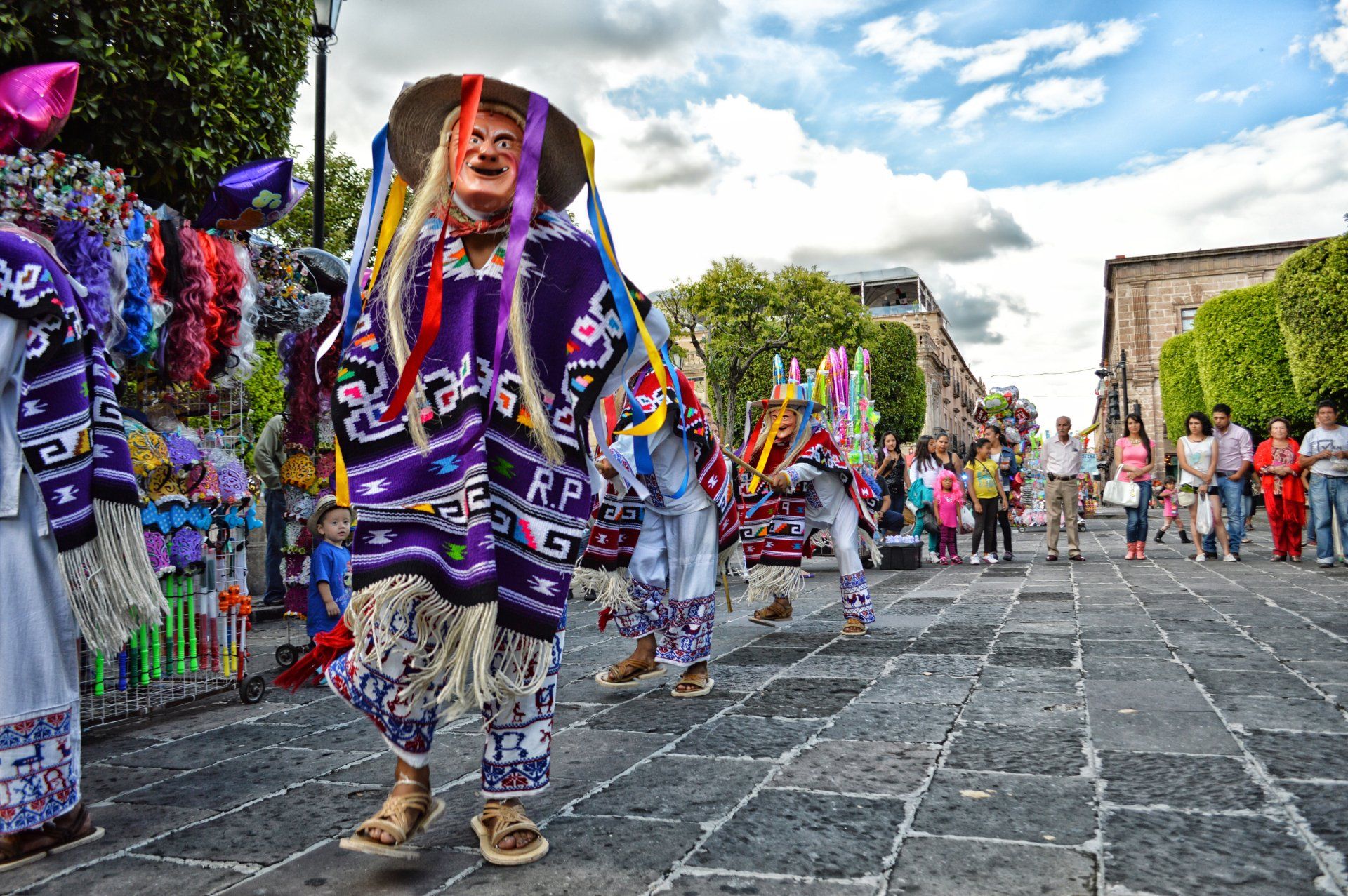 A group of people in colorful costumes are dancing on a street.