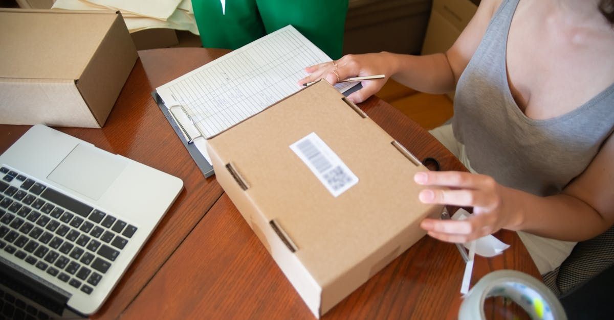 A woman is sitting at a table holding a cardboard box.