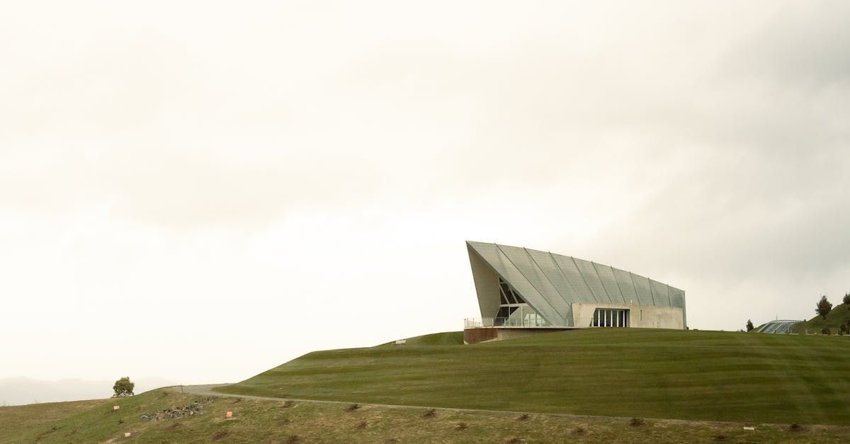 a large building is sitting on top of a grassy hill .
