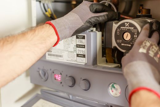 A man wearing gloves is working on a boiler.