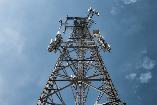 Looking up at a telephone tower with a blue sky in the background