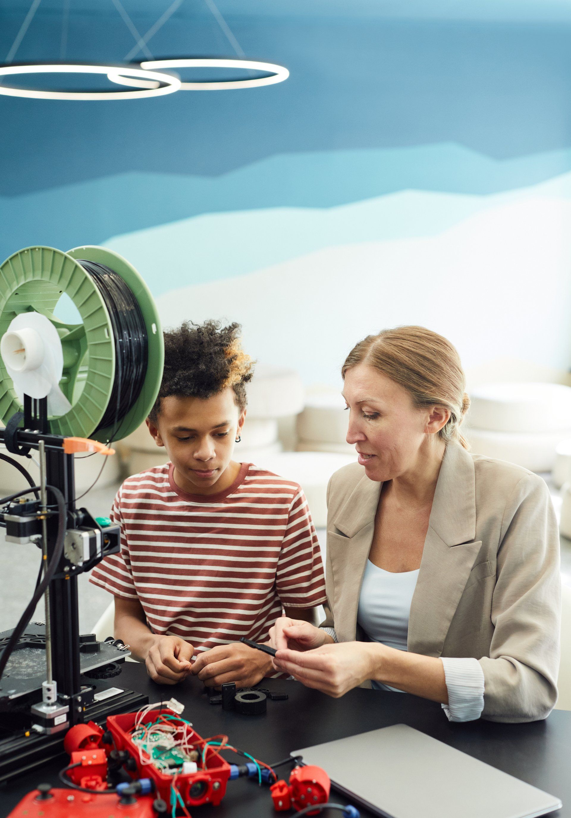 A woman is teaching a boy how to use a 3d printer.