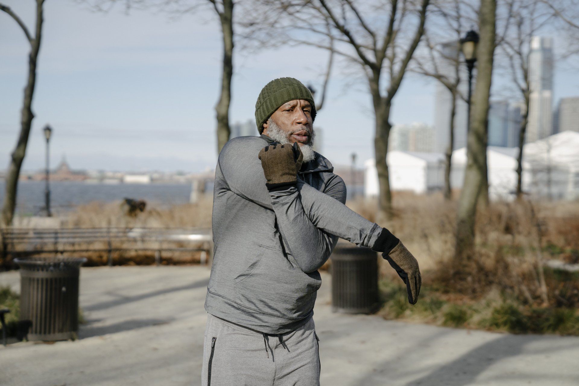 A man is stretching his arms in a park.