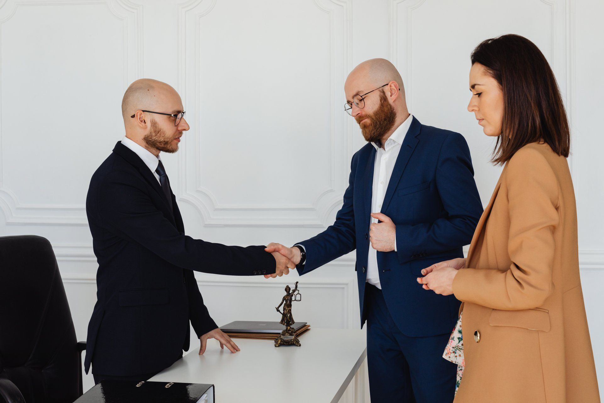 A man and a woman are shaking hands with a lawyer in an office.