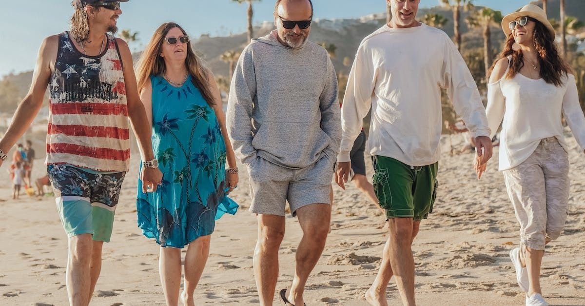 A group of people are walking on the beach holding hands.