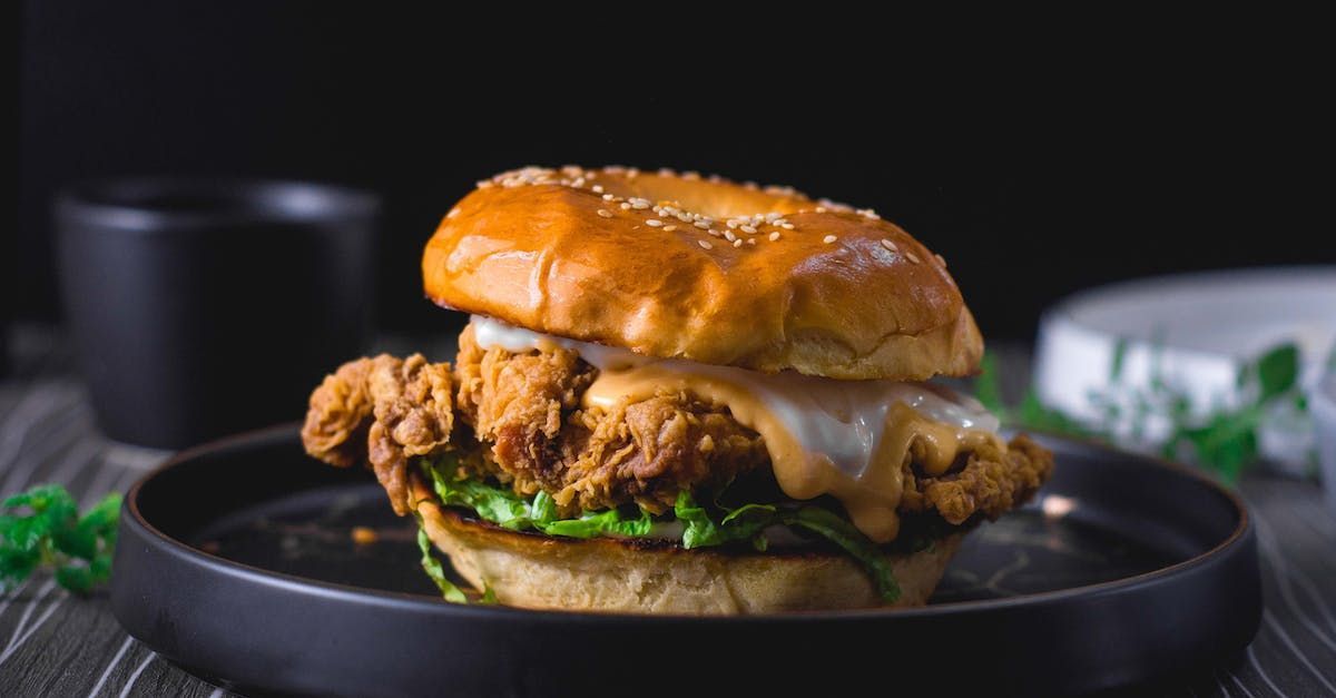 A close up of a chicken sandwich on a plate on a table.