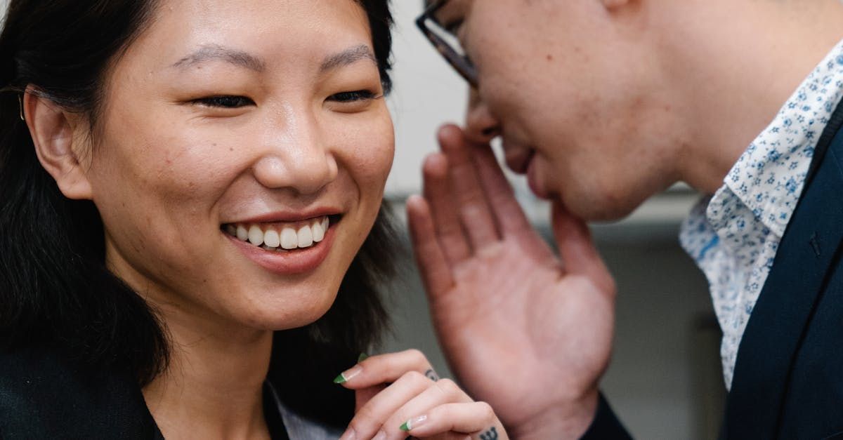 a man is whispering an oral agreement into a woman 's ear.