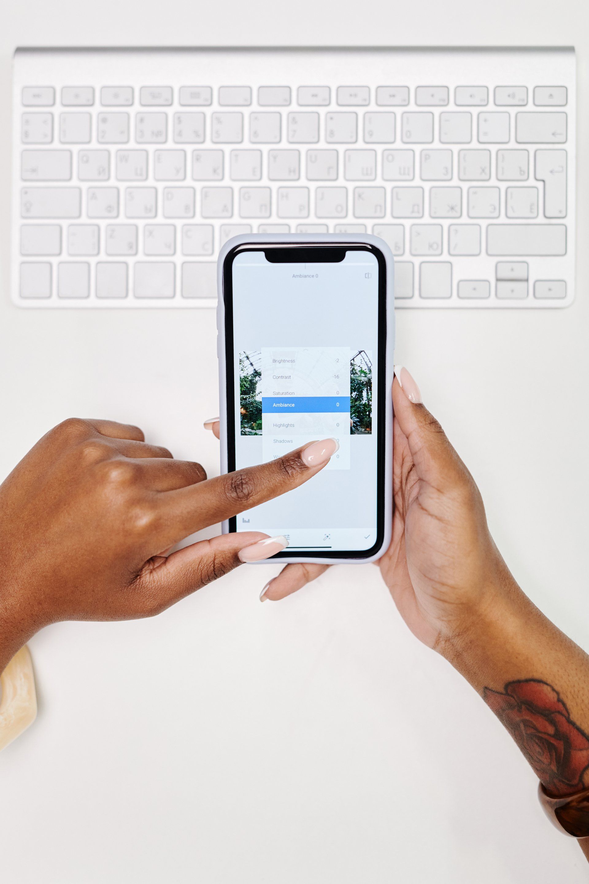 Une personne tient un téléphone portable devant un clavier.