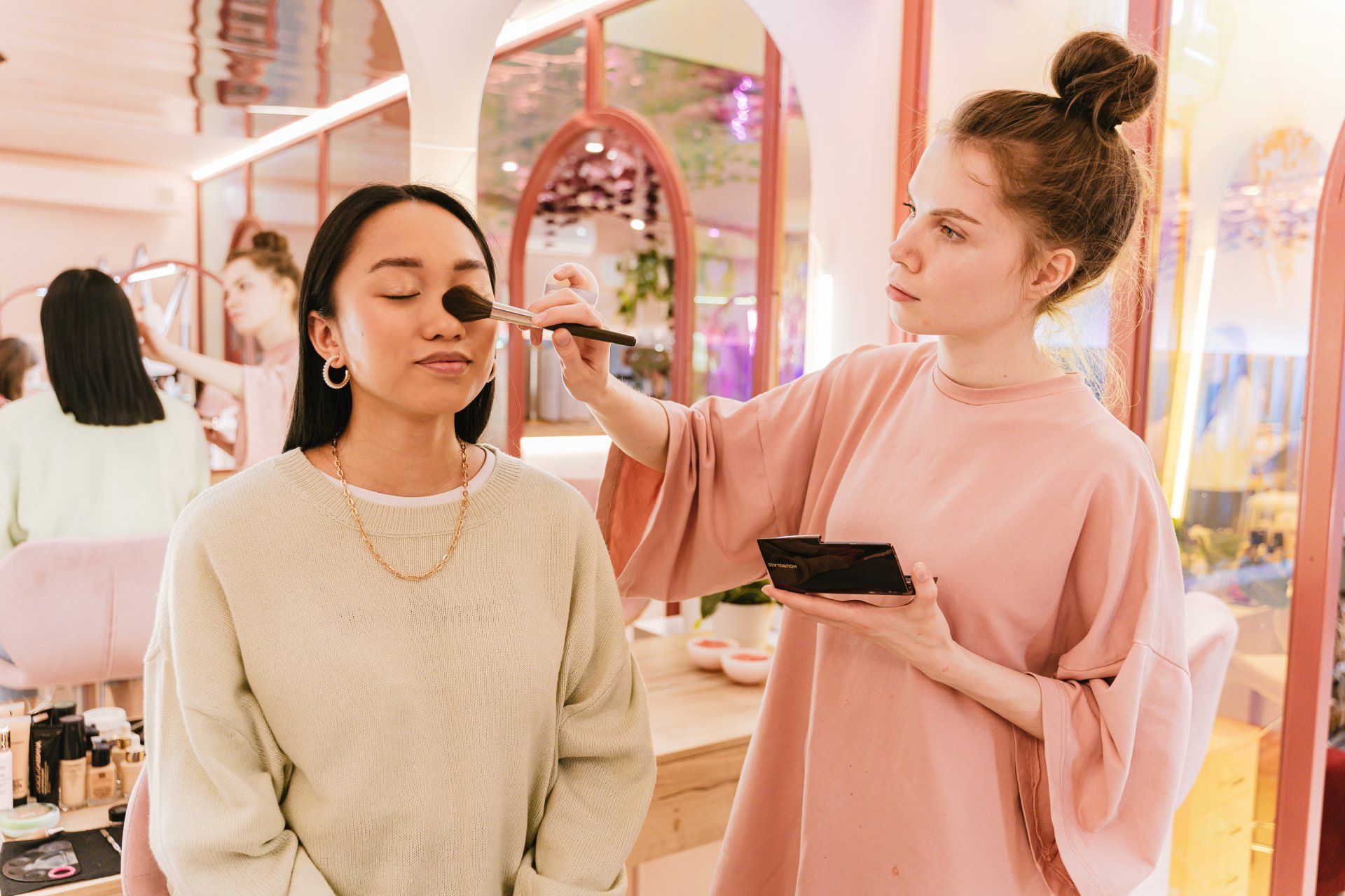 a woman is applying makeup to another woman 's face in a salon .