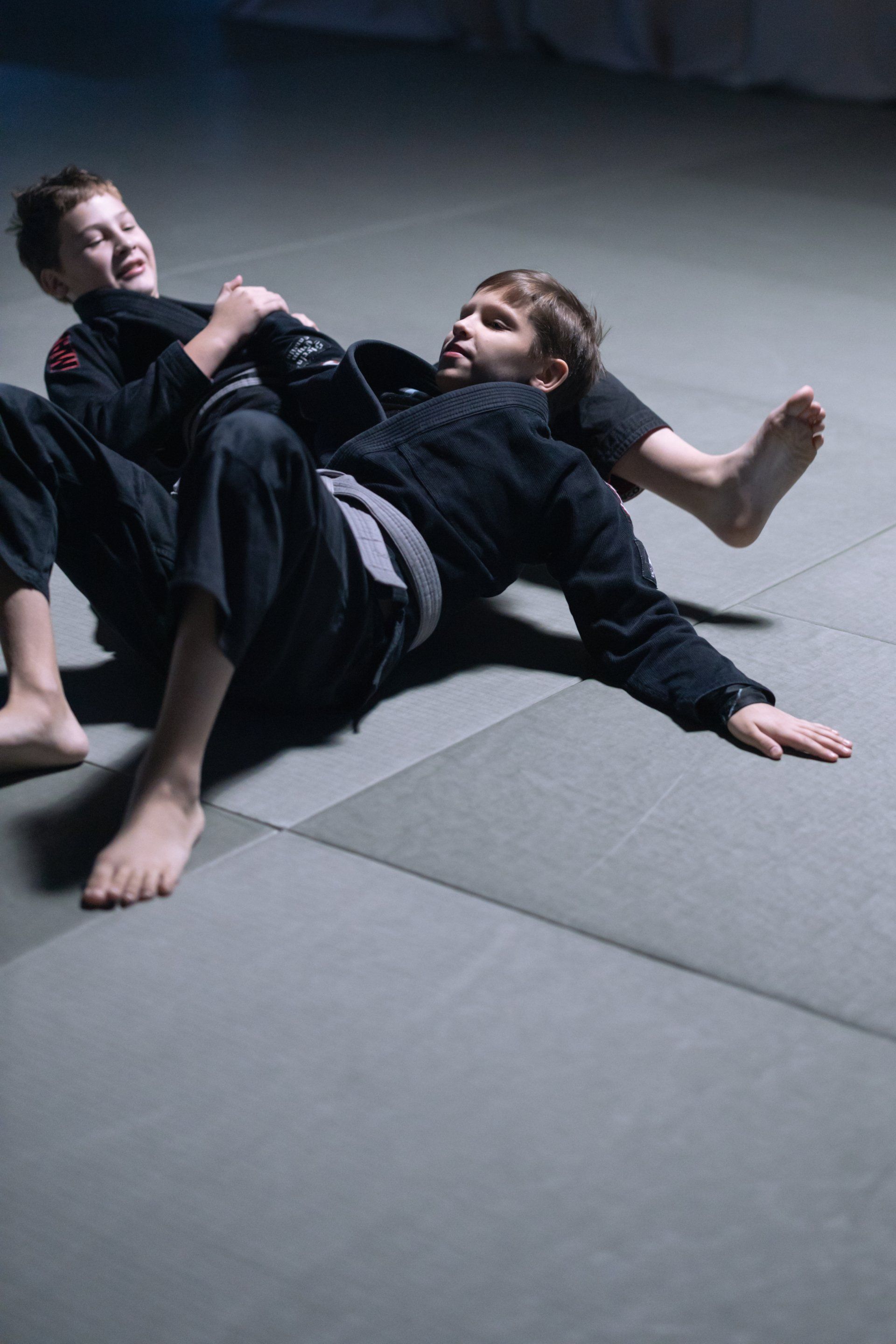 Two boys are wrestling on a mat in a gym.