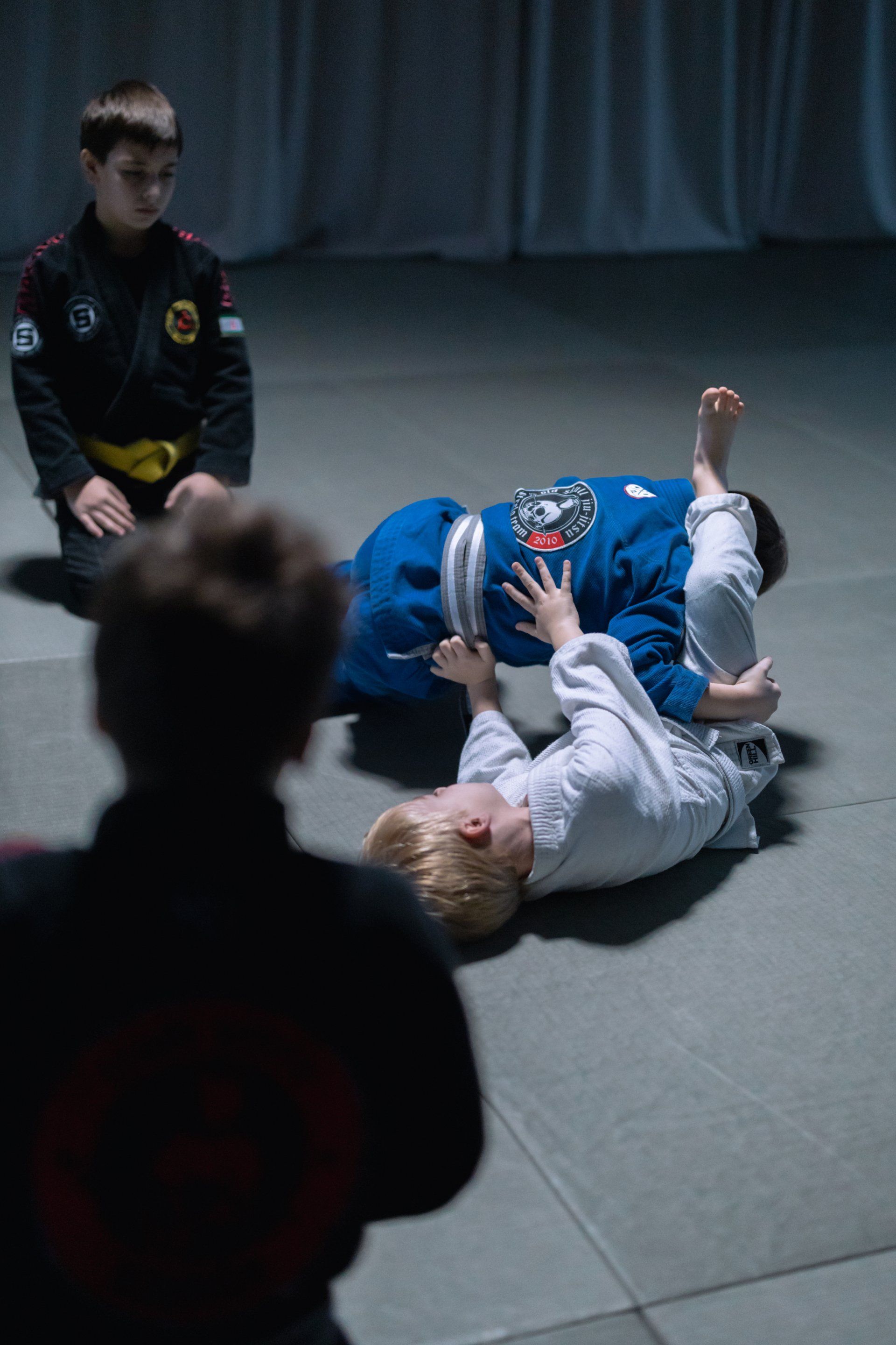 A group of young boys are practicing jiu jitsu in a gym.