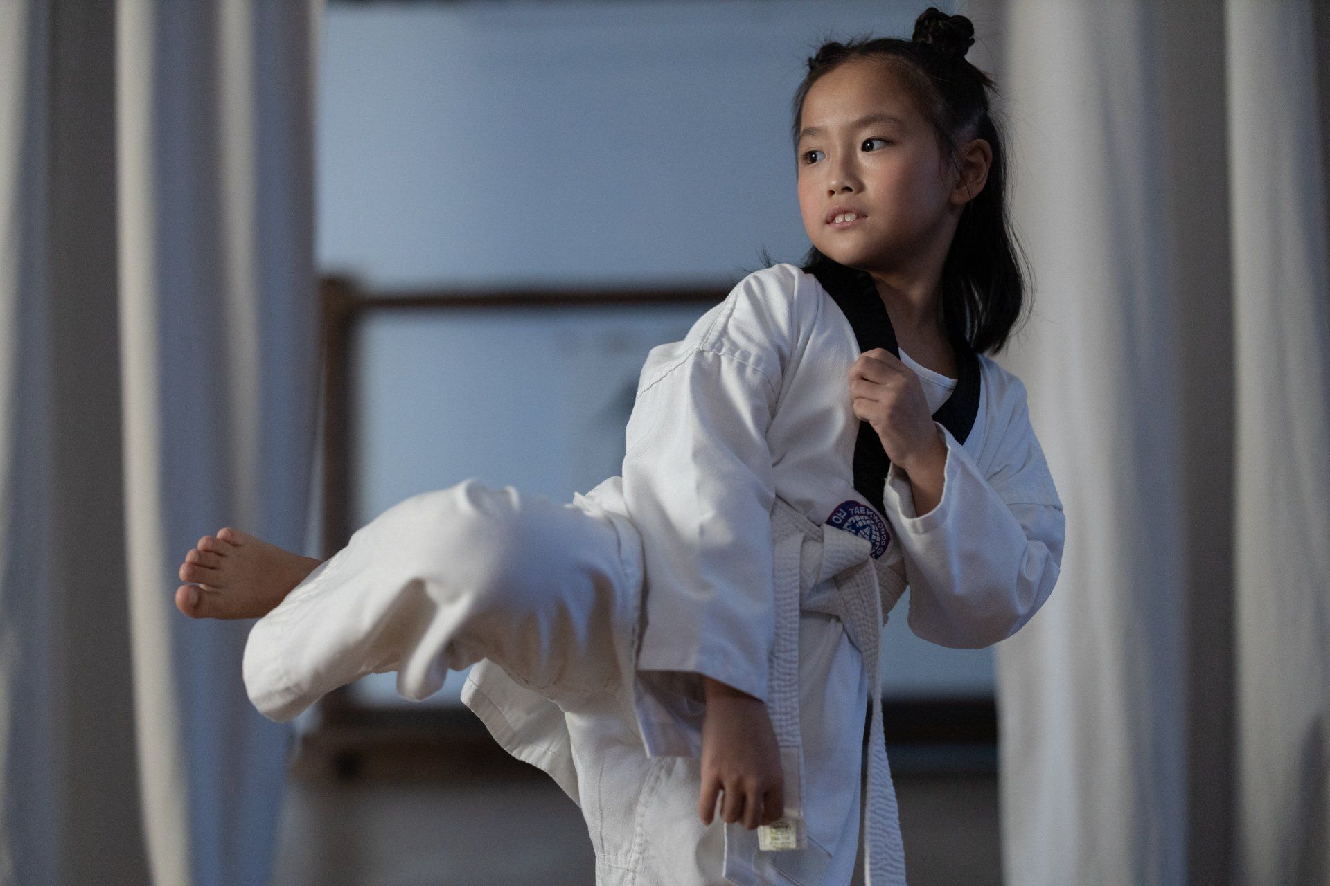 A young girl is practicing taekwondo in a gym.