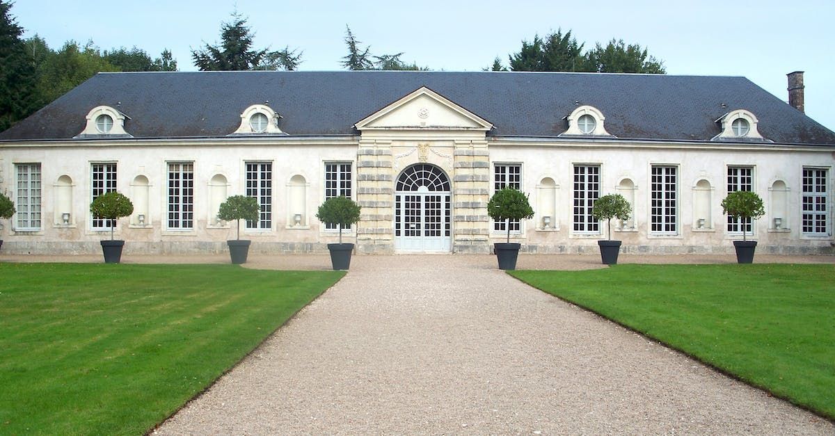 A large white building with a gravel driveway leading to it