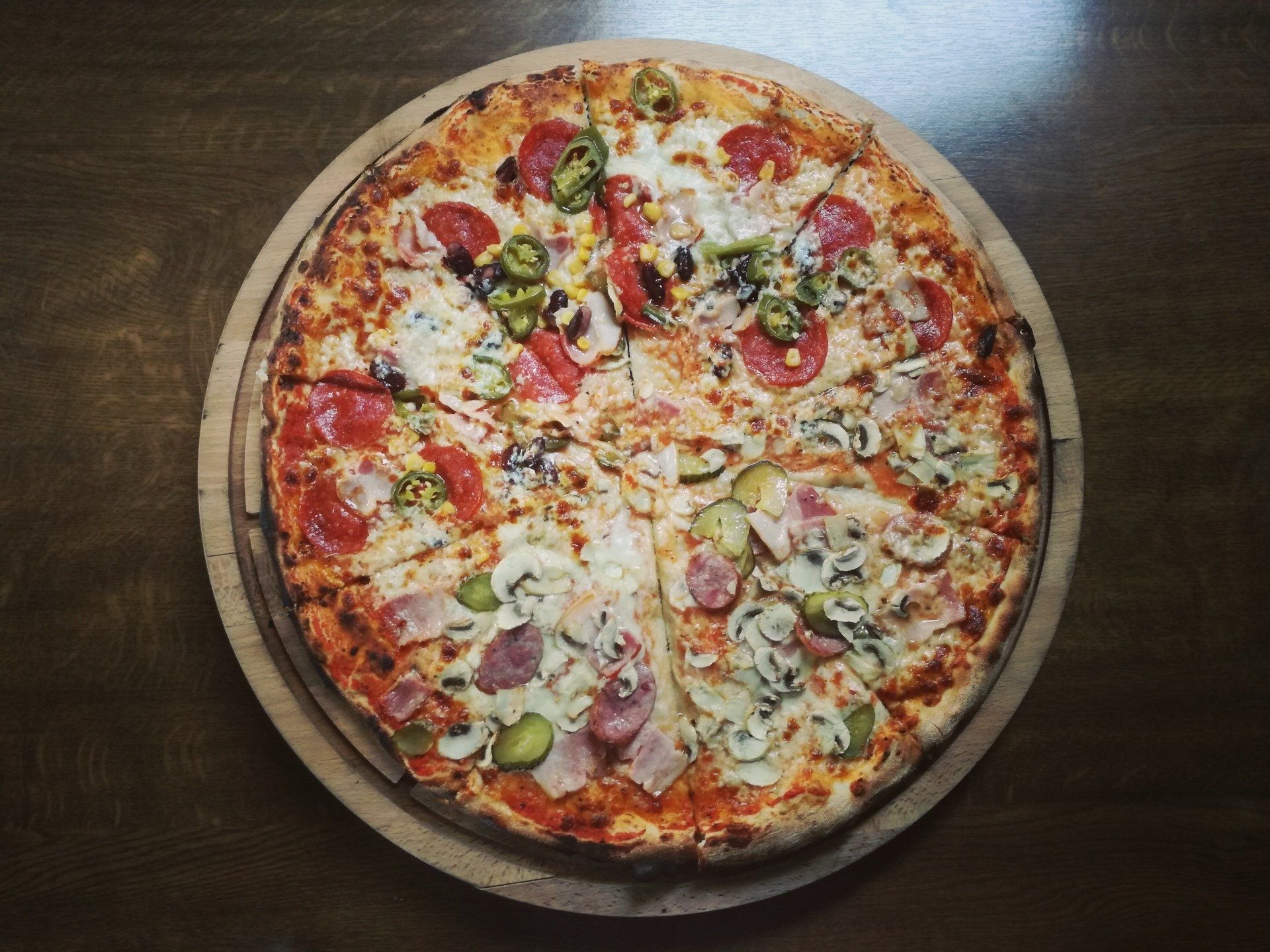 A pizza is sitting on a wooden cutting board on a wooden table.