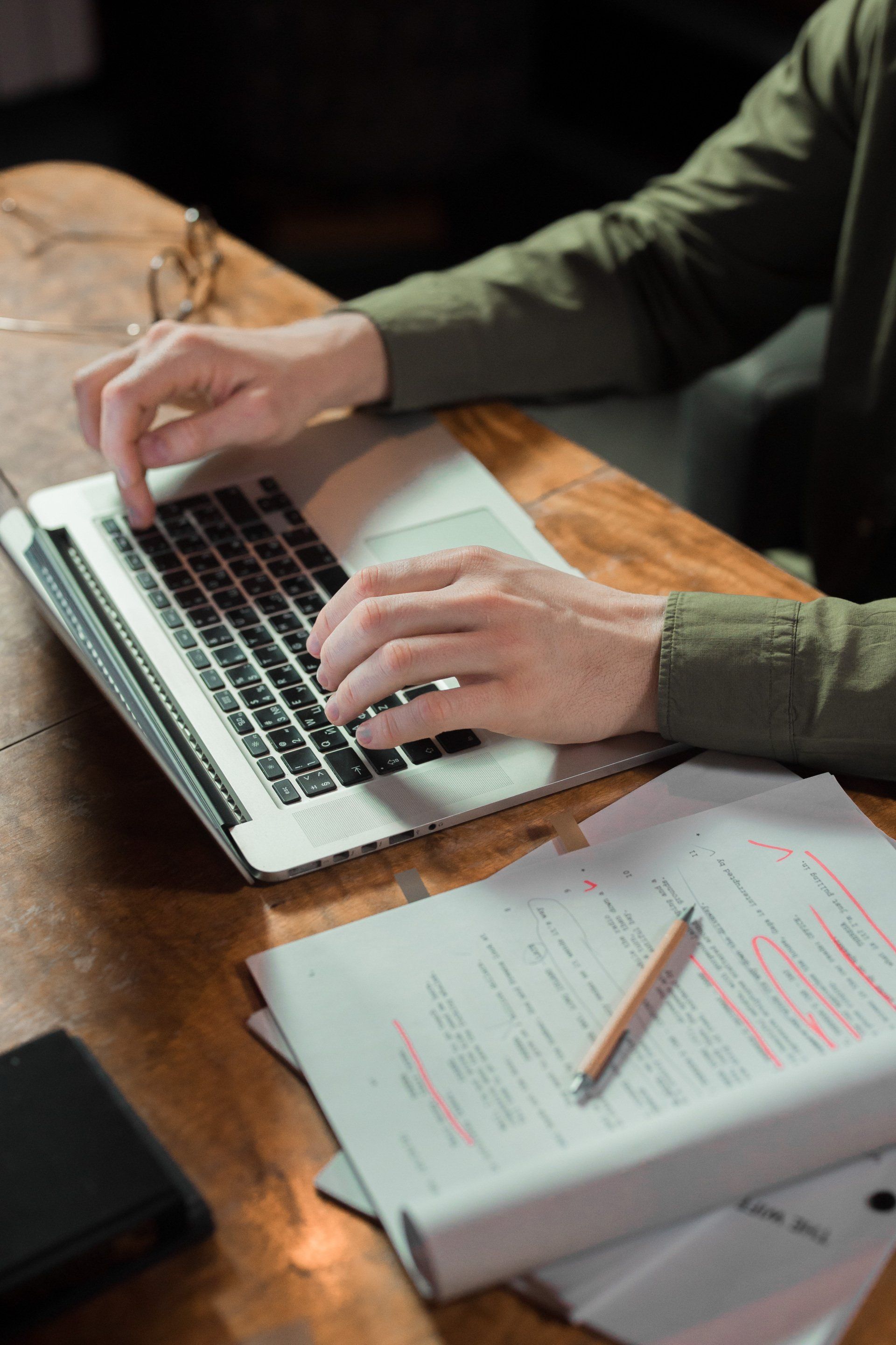A person is typing on a laptop computer at a desk.