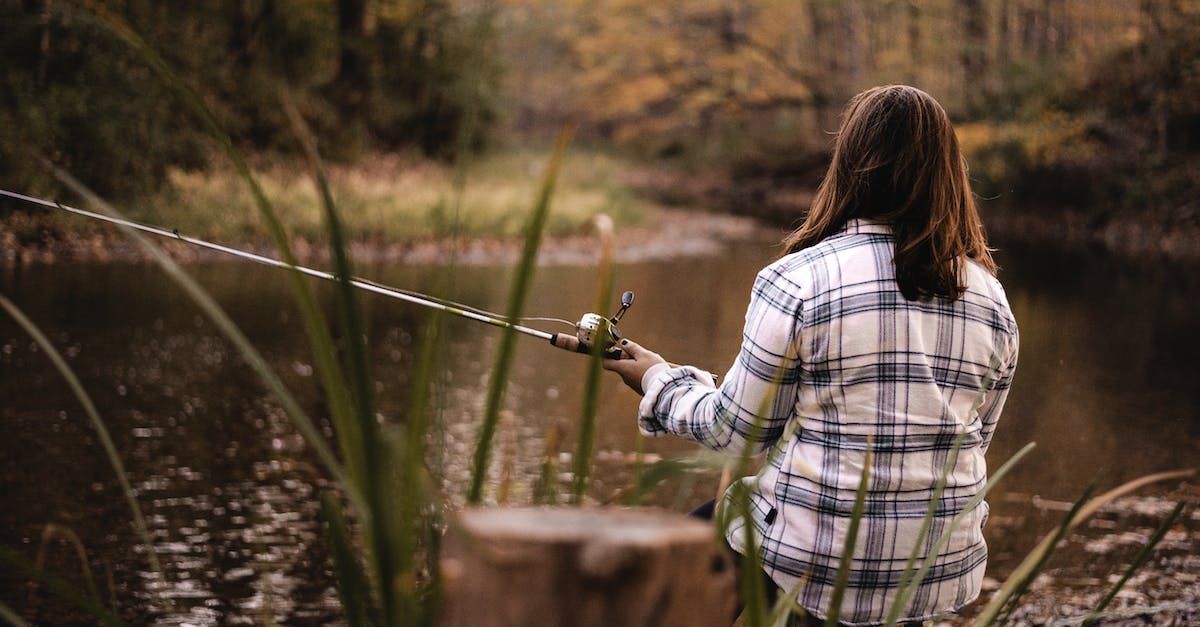 a woman is fishing in a pond with a fishing rod .
