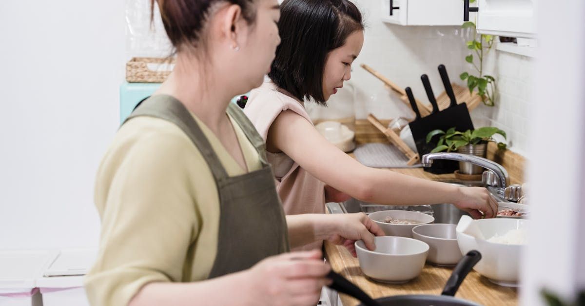 A woman and a child are washing dishes in a kitchen. NDIS support in Gungahlin and Canberra-Wide