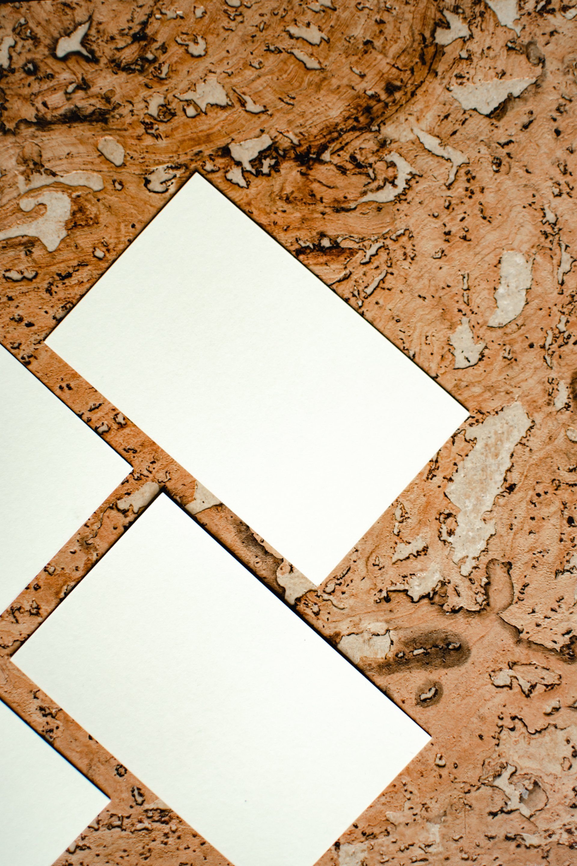 Three business cards are stacked on top of each other on a cork surface.