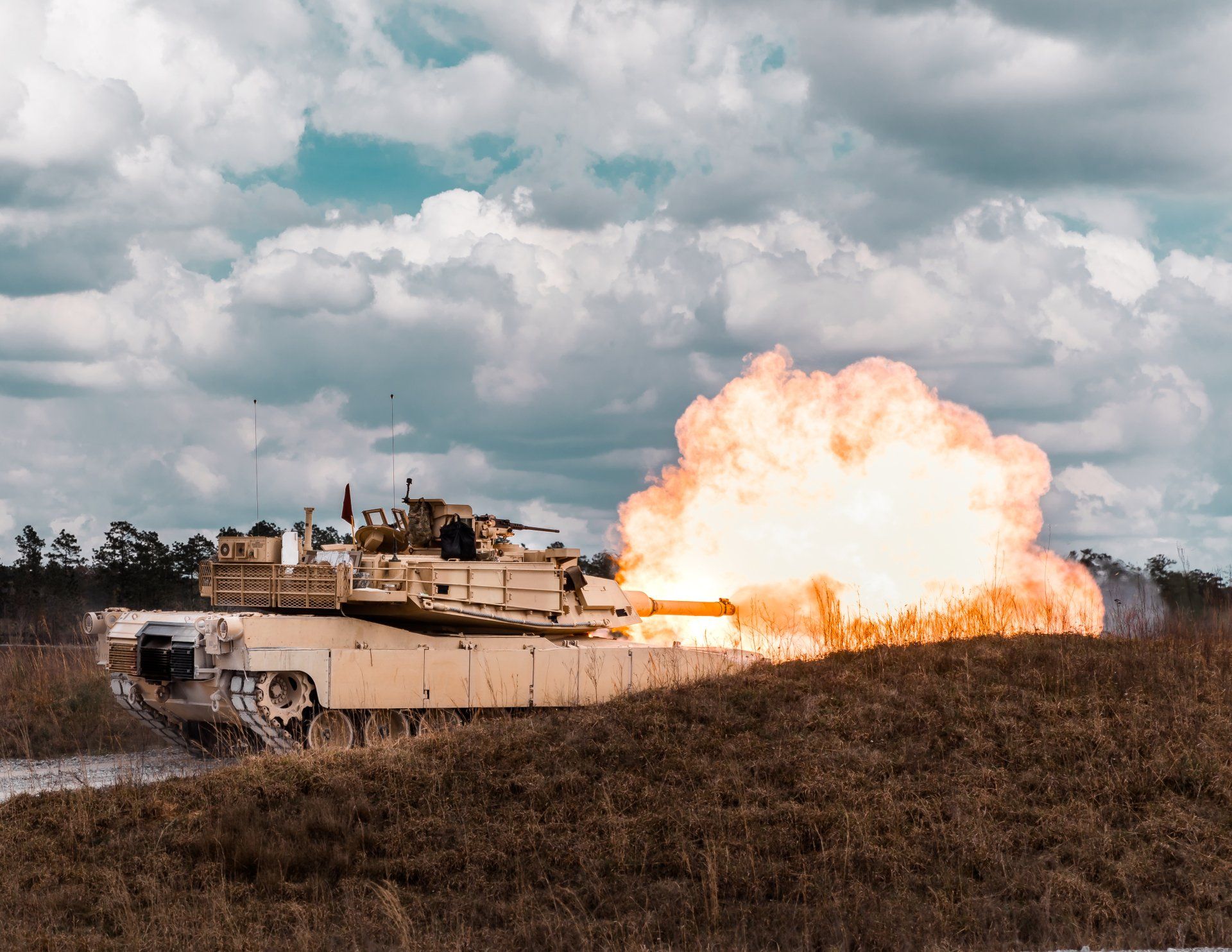 A military tank is firing a rocket in a field.