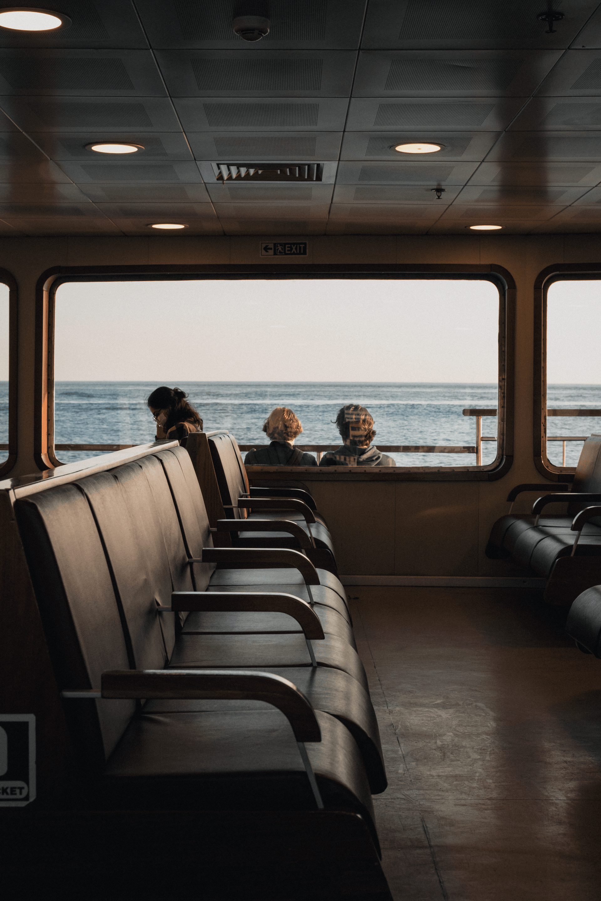 A group of people are sitting on a boat looking out a window at the ocean.