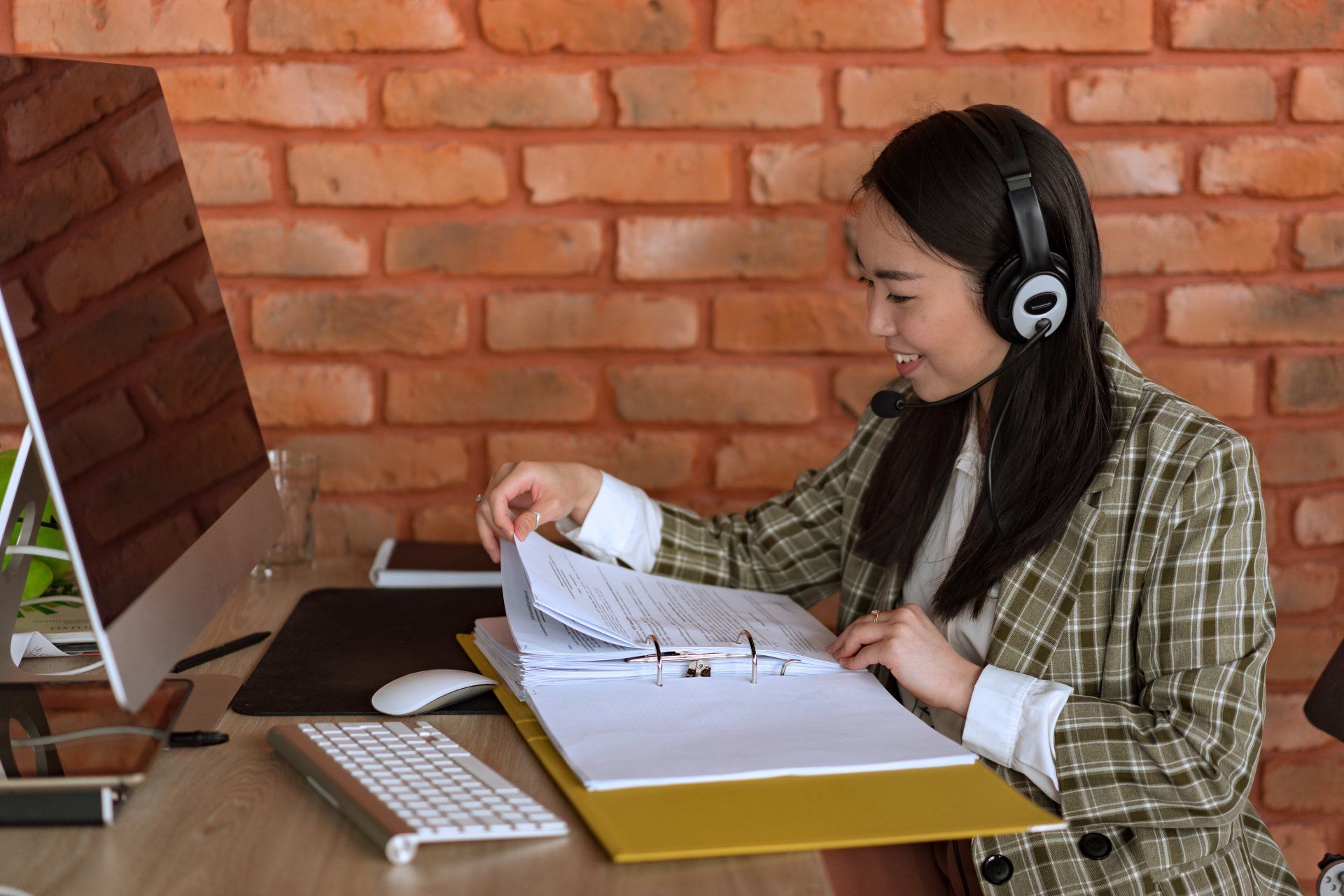 An Image of a woman in front of a desktop computer with paperwork's at Overseas Filipino Workers