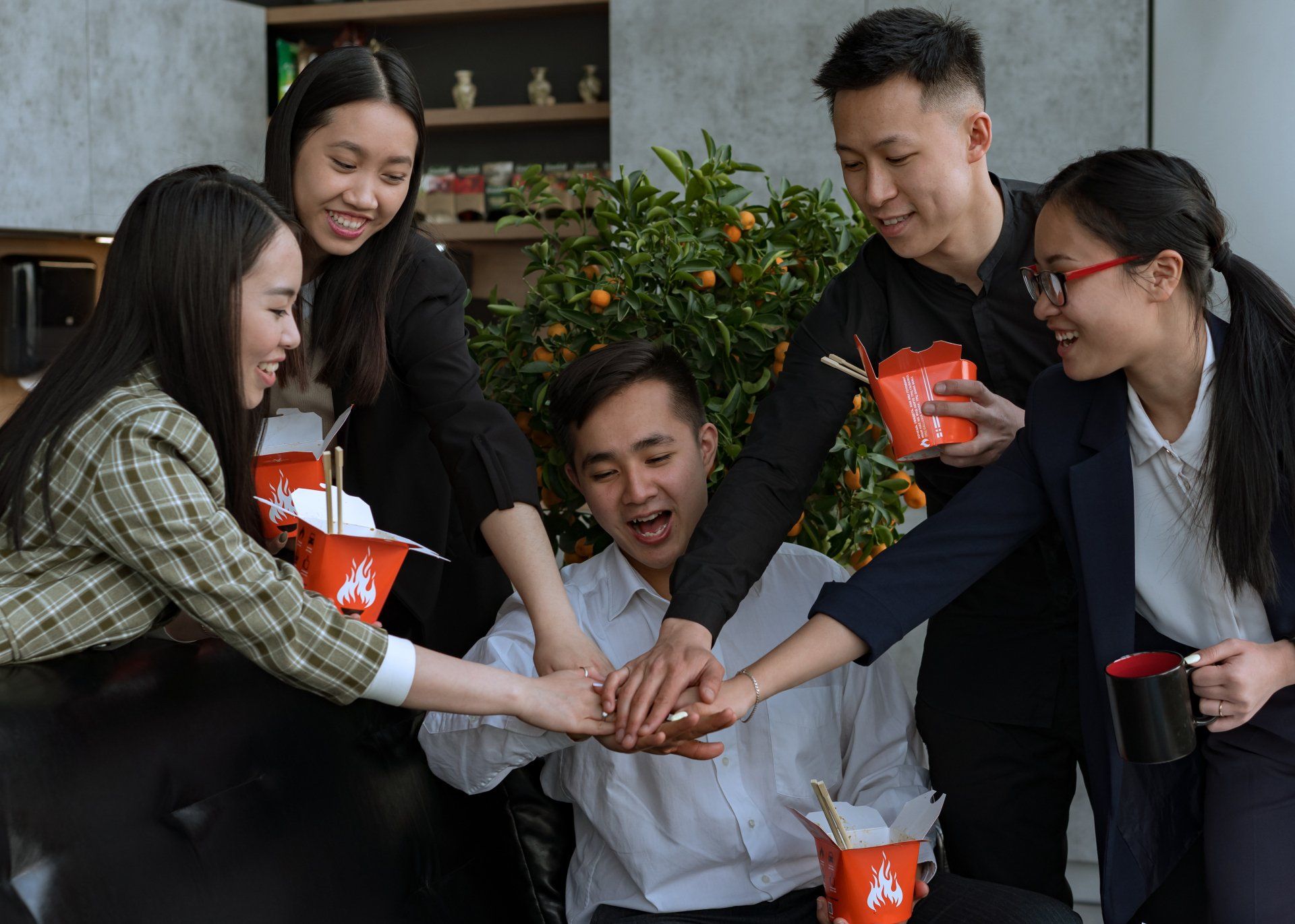 Multiple Asian co-workers putting their hands together in a huddle