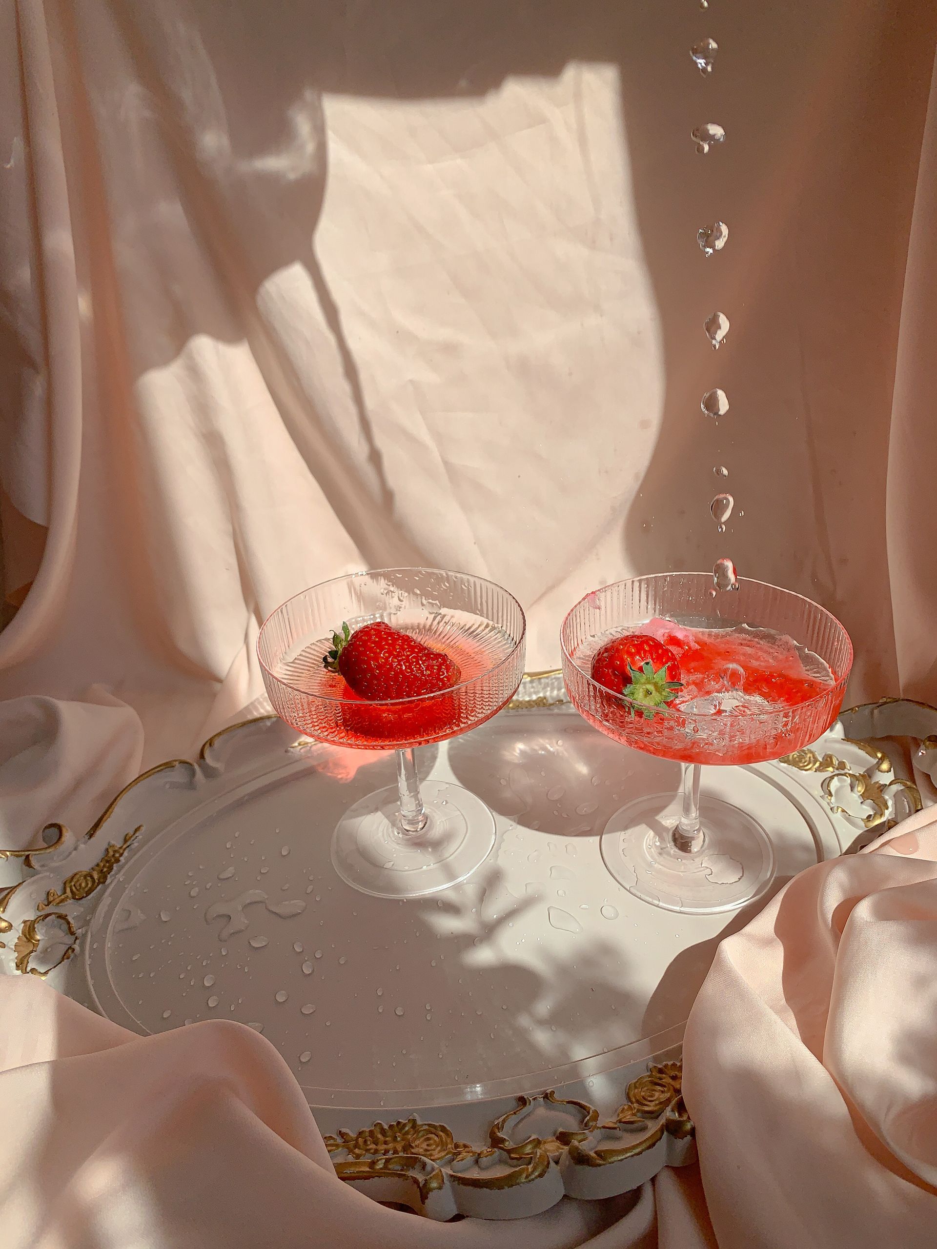 Two champagne glasses filled with strawberries on a tray.