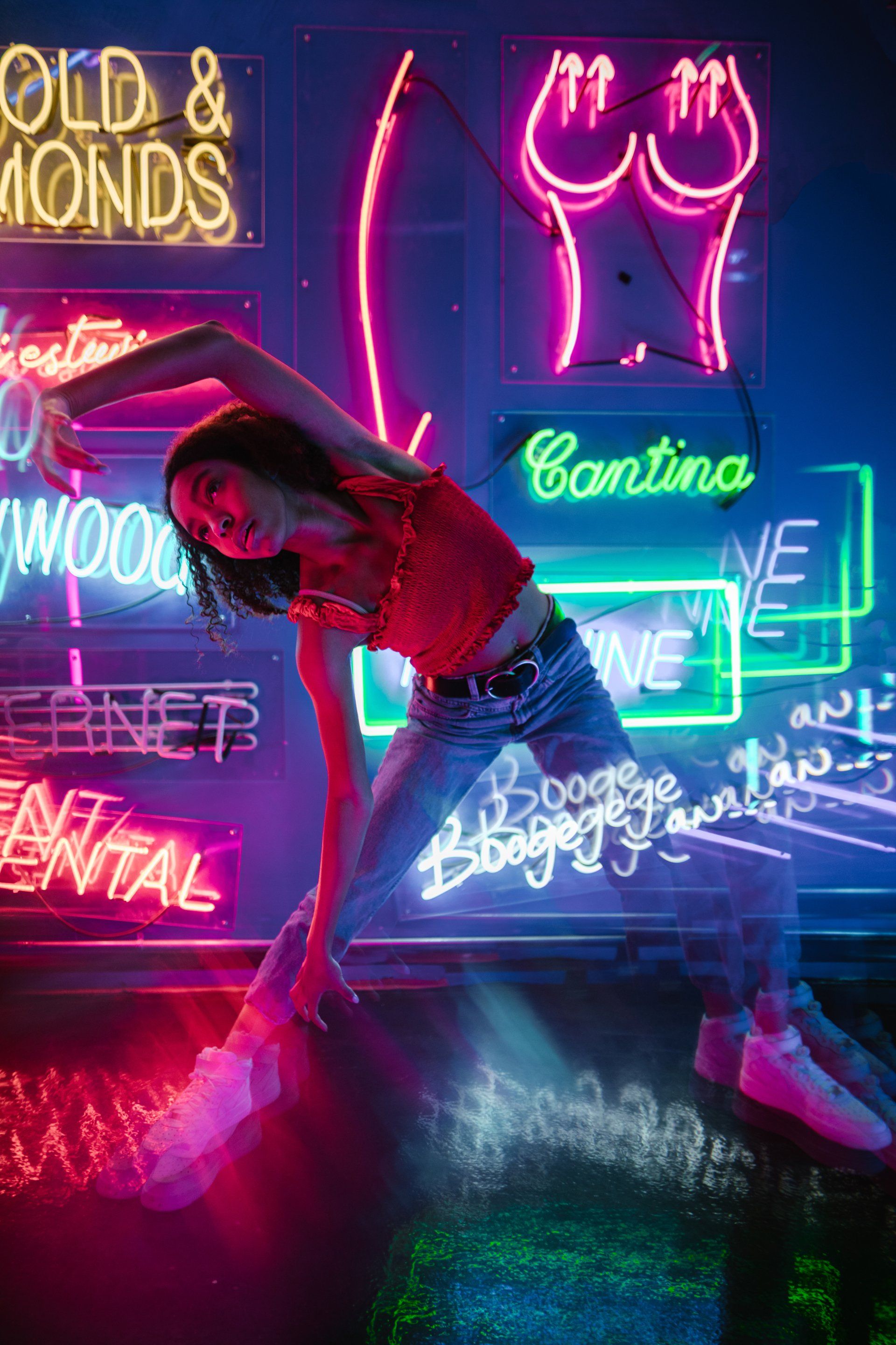 A woman is dancing in front of a neon sign.